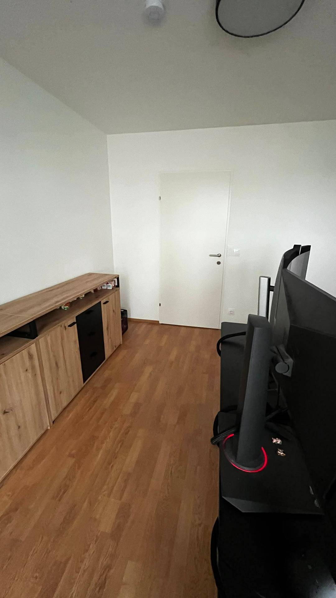 Funktionales Arbeitszimmer mit langen Holzschränken und einer Tür, bietet viel Stauraum.