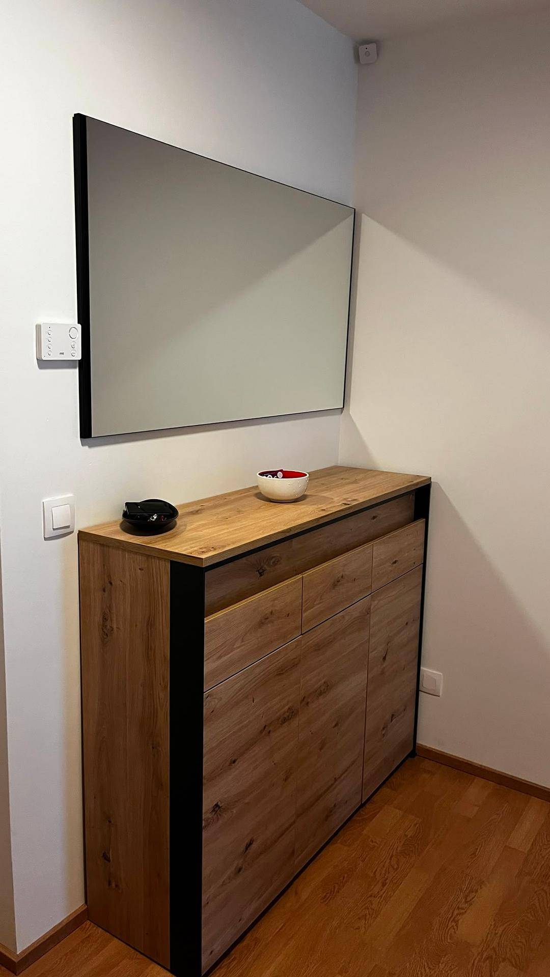 Stilvoller Schuhschrank mit Holzoberfläche und großem Wandspiegel im modernen Eingangsbereich.