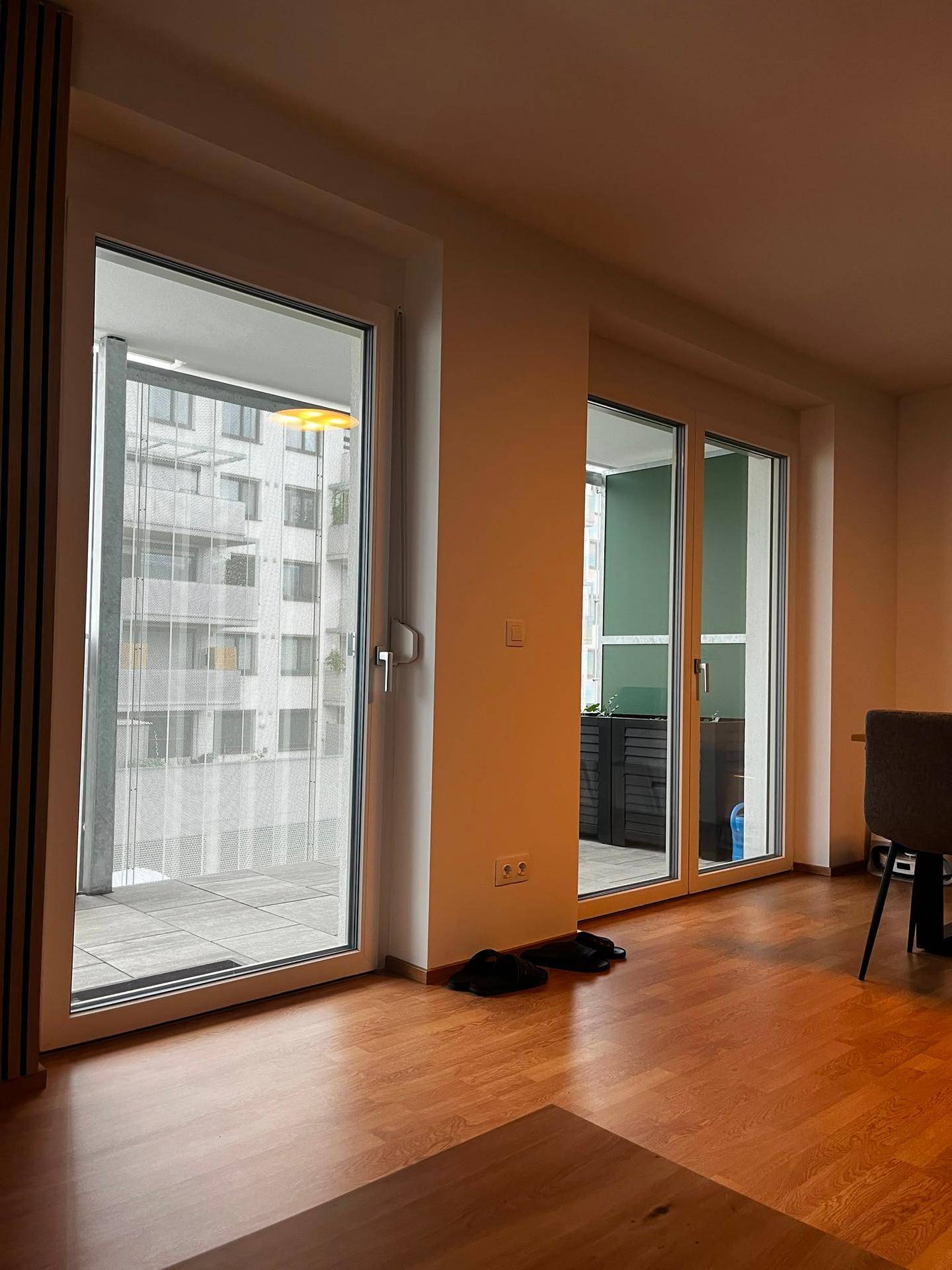 Helle Fensterfront mit Zugang zu einem geräumigen Balkon, bietet viel Tageslicht und Ausblick.