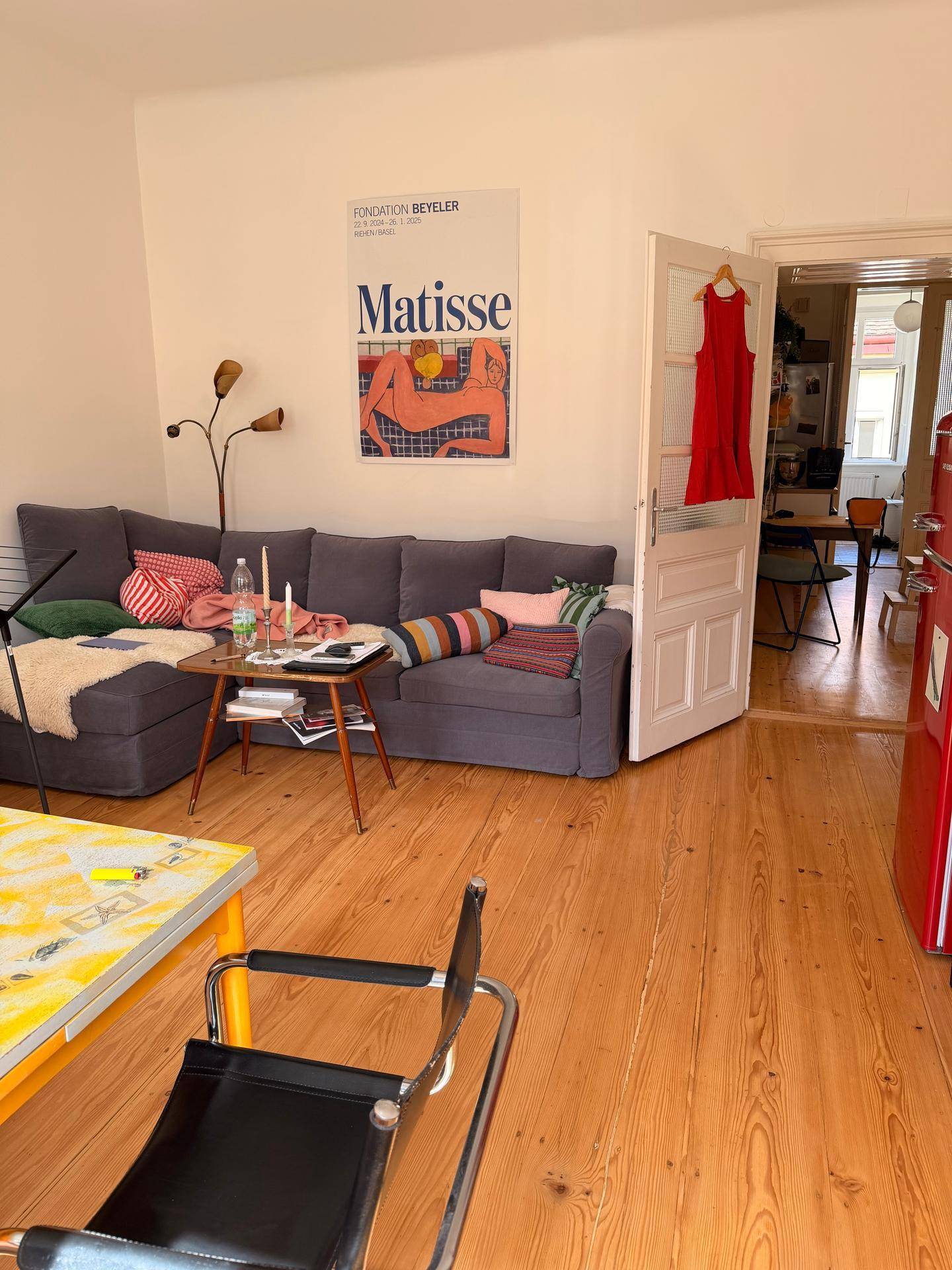 Gemütliches Wohnzimmer mit Ecksofa, Holzboden und Kunstposter an der Wand.