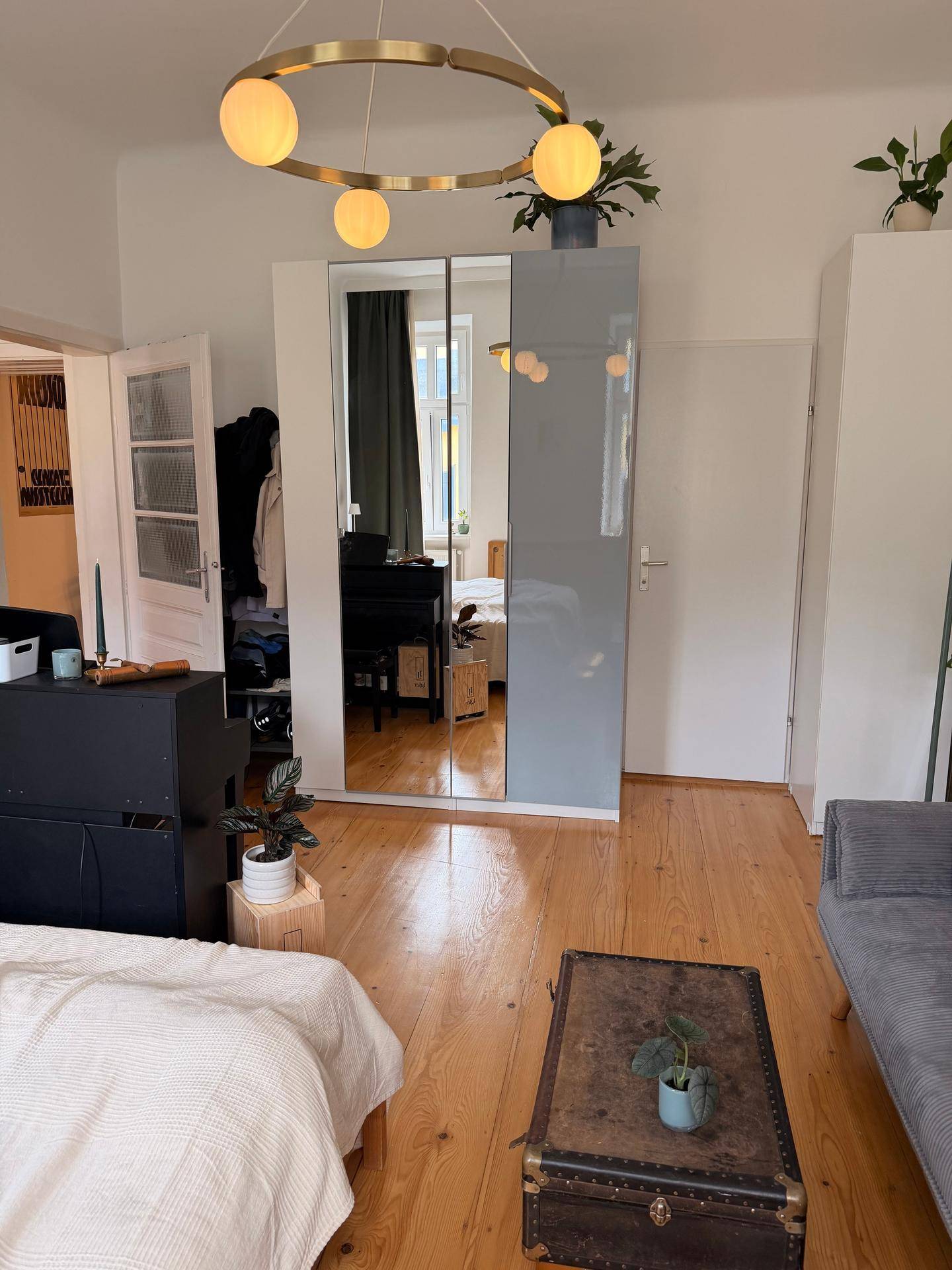 Wohnbereich mit Spiegelschrank, Holzboden und modernem Deckenlicht.