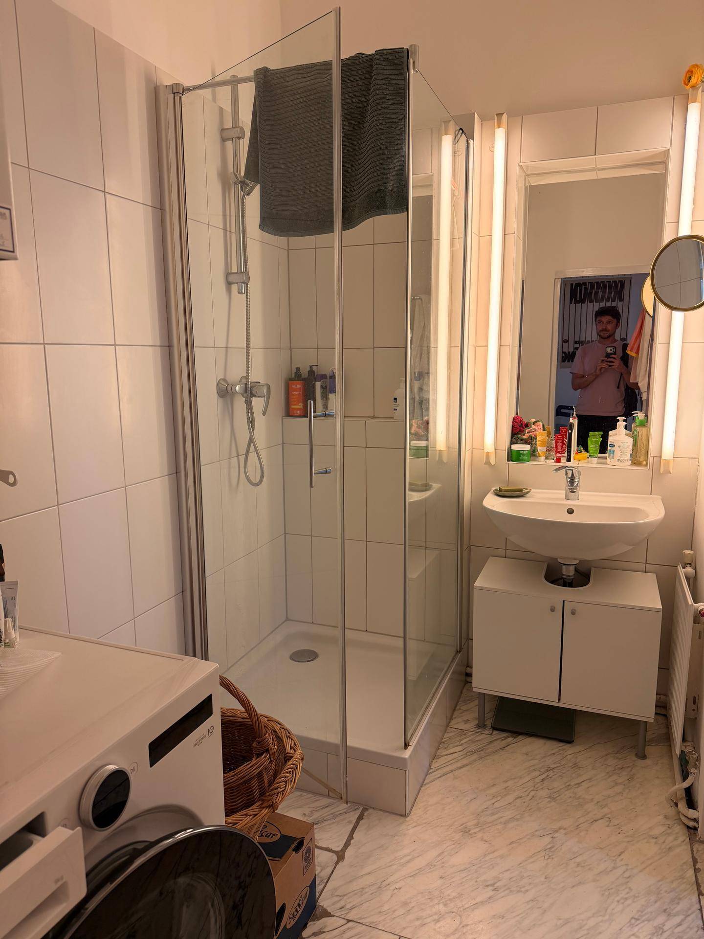 Funktionales Badezimmer mit Duschkabine, Waschbecken und Waschmaschine.
