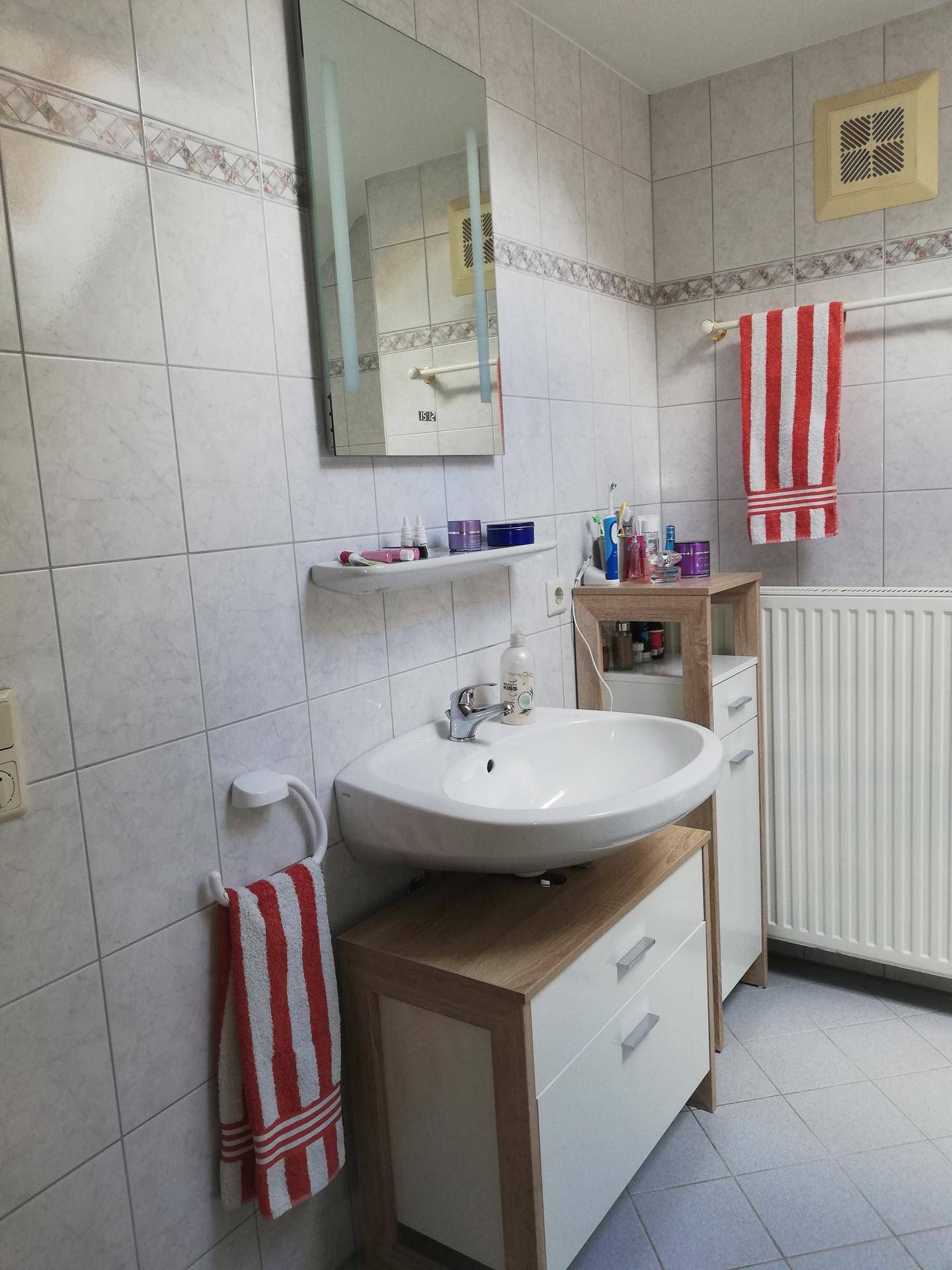 Funktionales Badezimmer mit hellen Fliesen, modernem Waschbecken und Heizkörper.