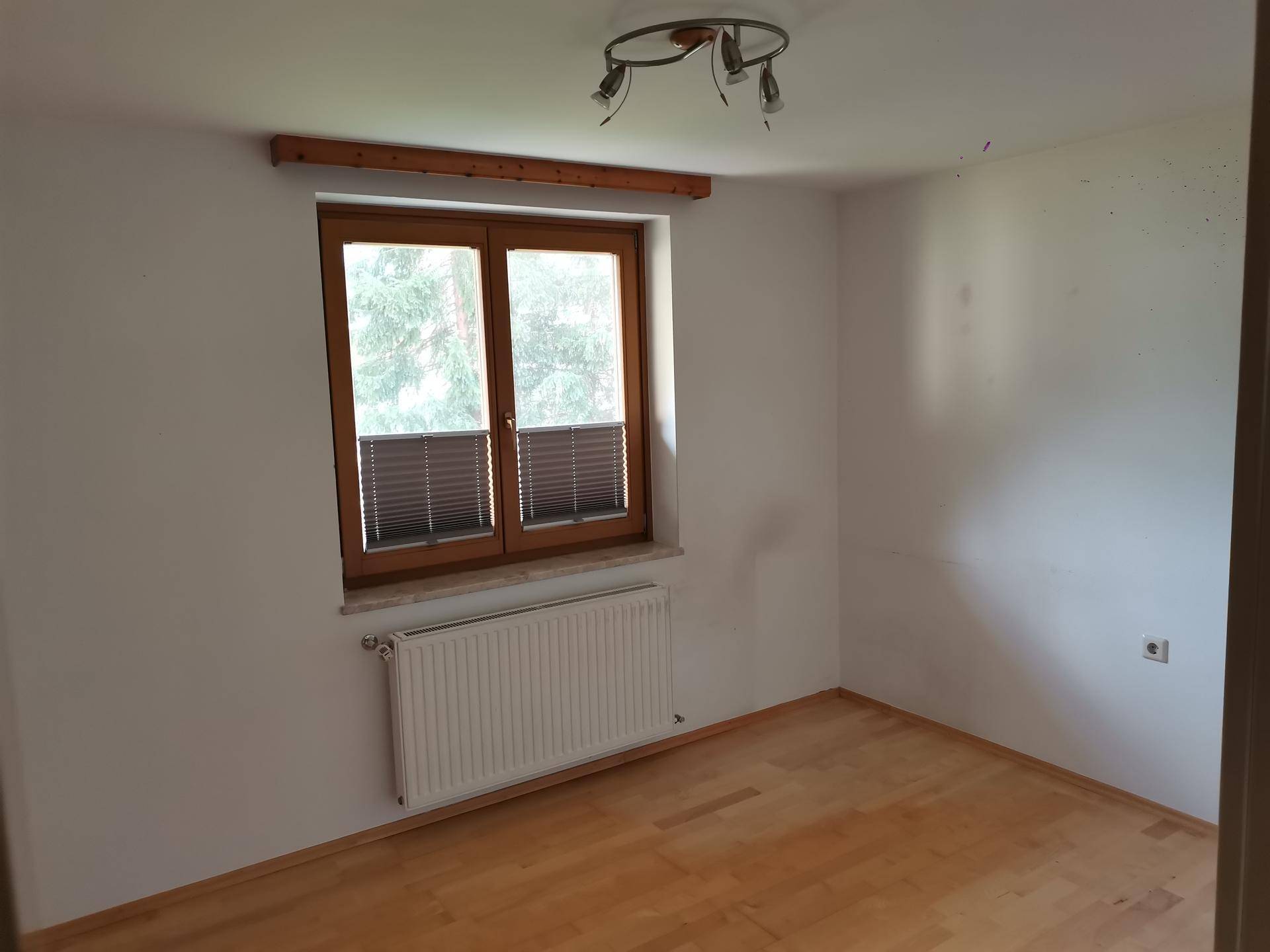 Geräumiges Schlafzimmer mit Parkettboden und großem Fenster, das viel Tageslicht hereinlässt.