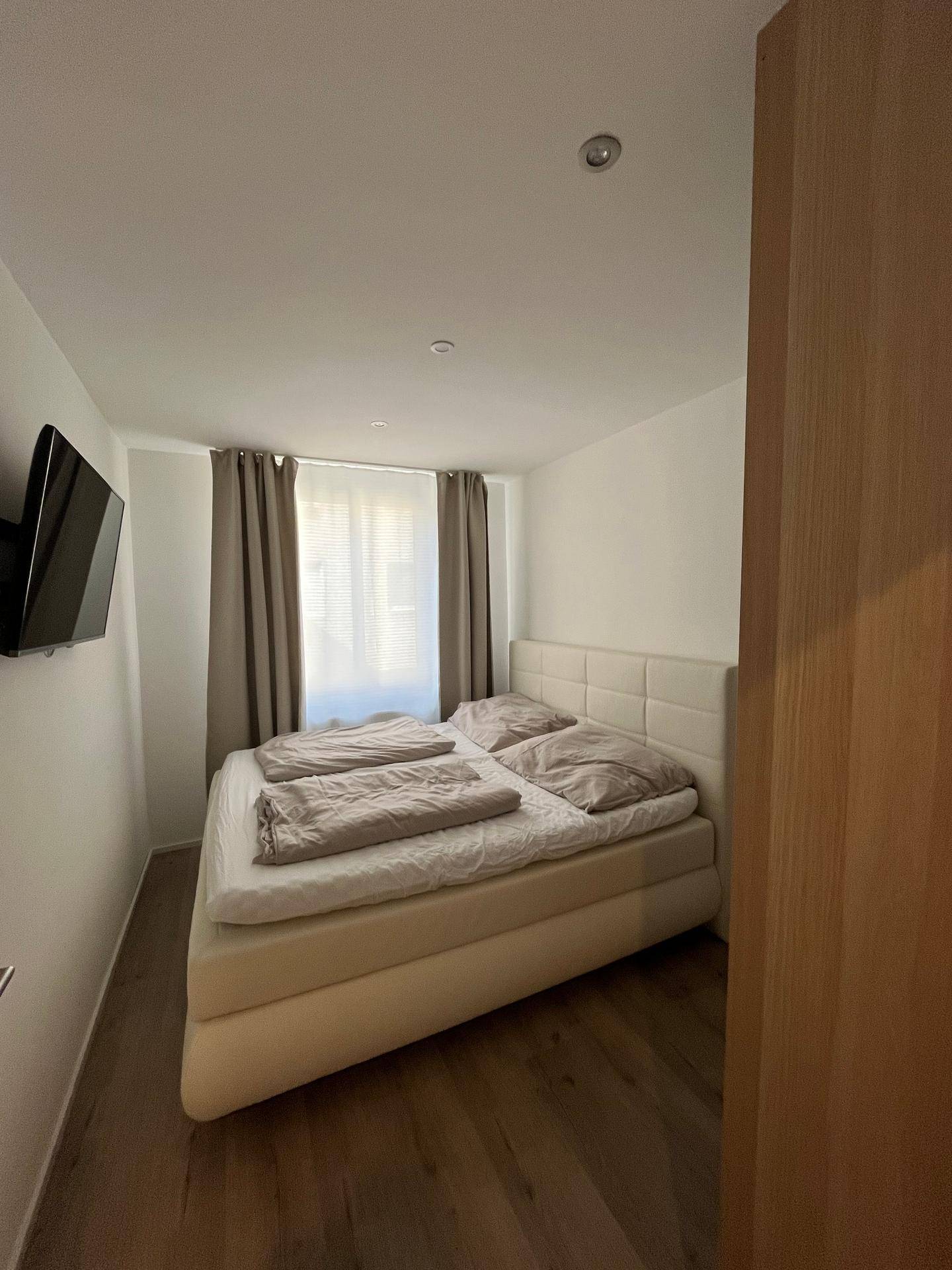 Schlafzimmer mit komfortablem Doppelbett und hellem Laminatboden, ideal für erholsame Nächte.