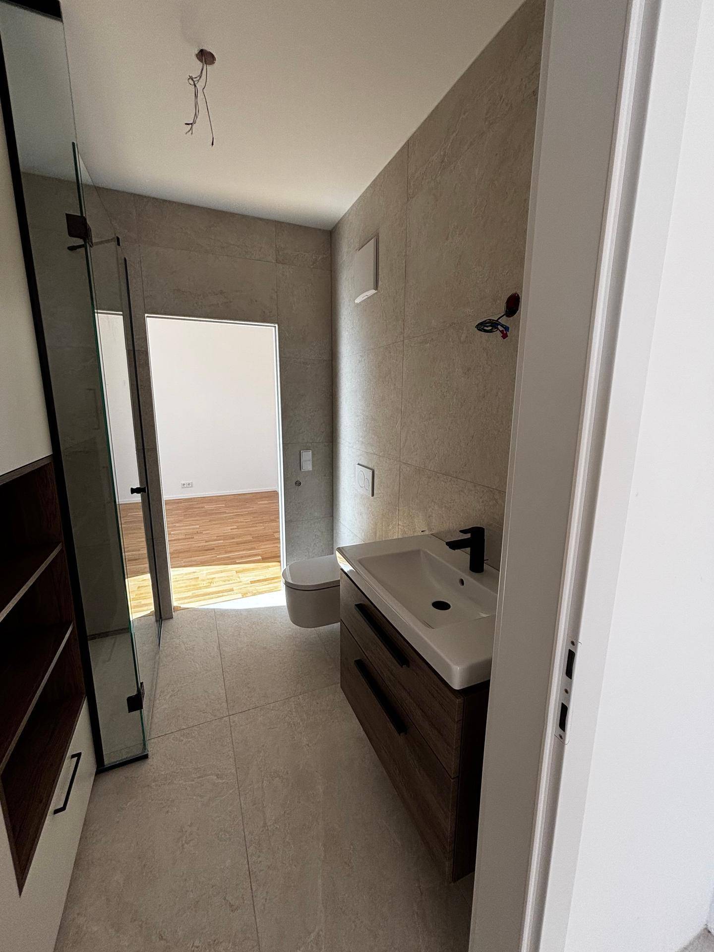 Geräumiges Badezimmer mit modernem Waschtisch, wandhängendem WC und begehbarer Dusche.