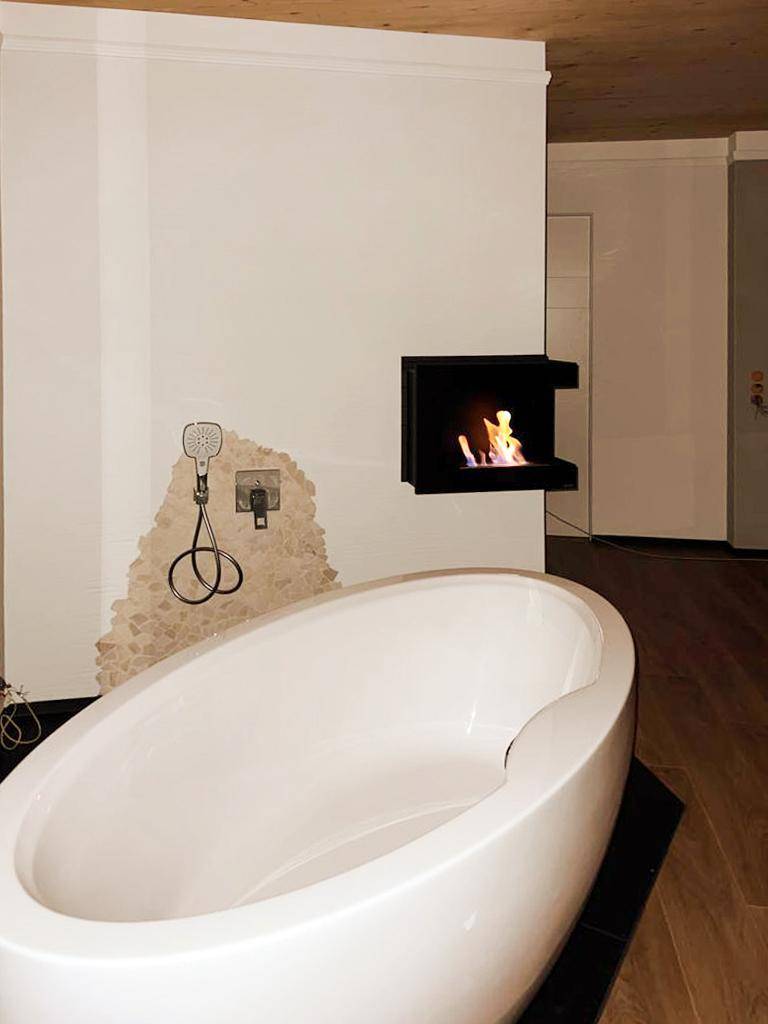 Badezimmer mit freistehender Badewanne, Wanddusche und integriertem Kamin.