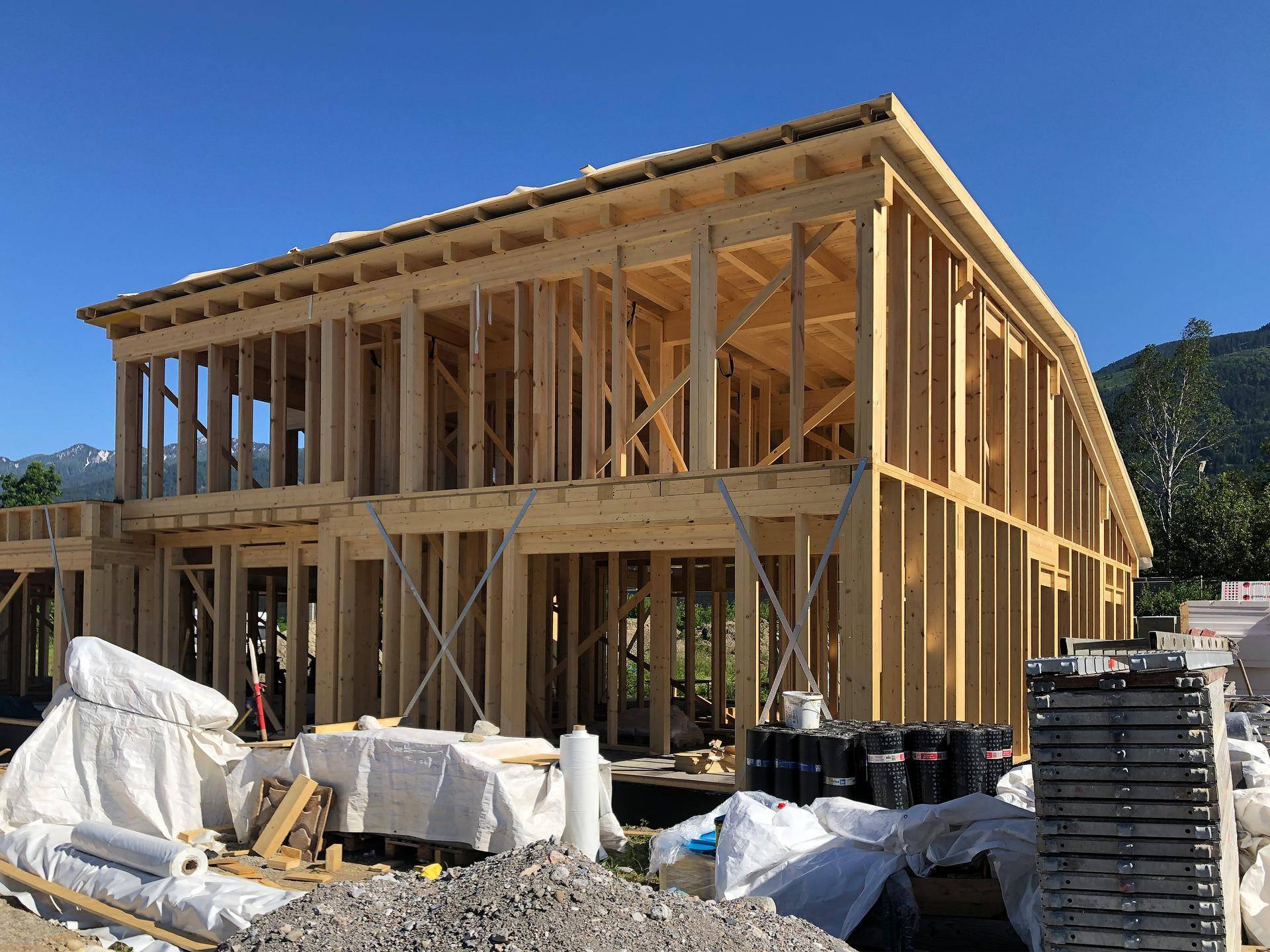 Holzrahmenbau eines modernen Hauses im Bau mit sichtbaren Holzbalken und Gerüst.