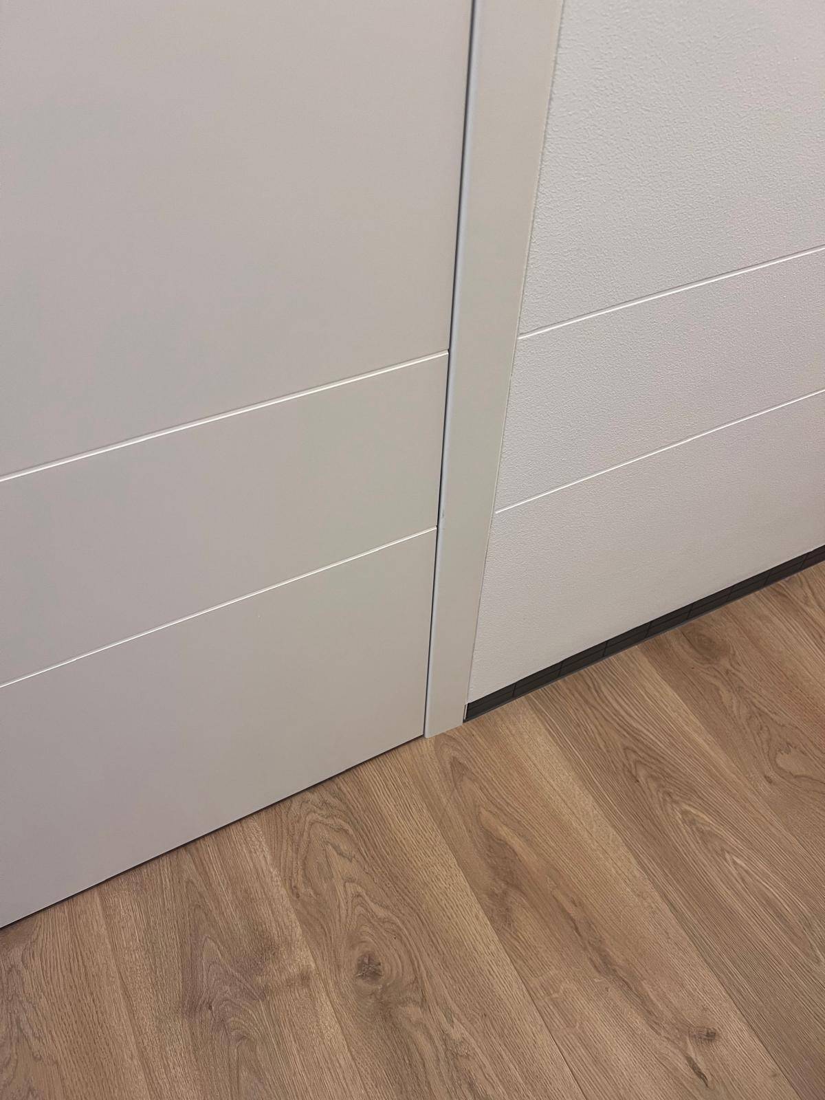 Detailansicht einer modernen weißen Tür mit Holzboden und minimalistischer Ästhetik.