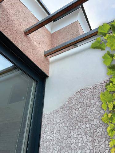 Detailansicht der modernen Fassade mit Mosaikakzenten und Pergola-Struktur.