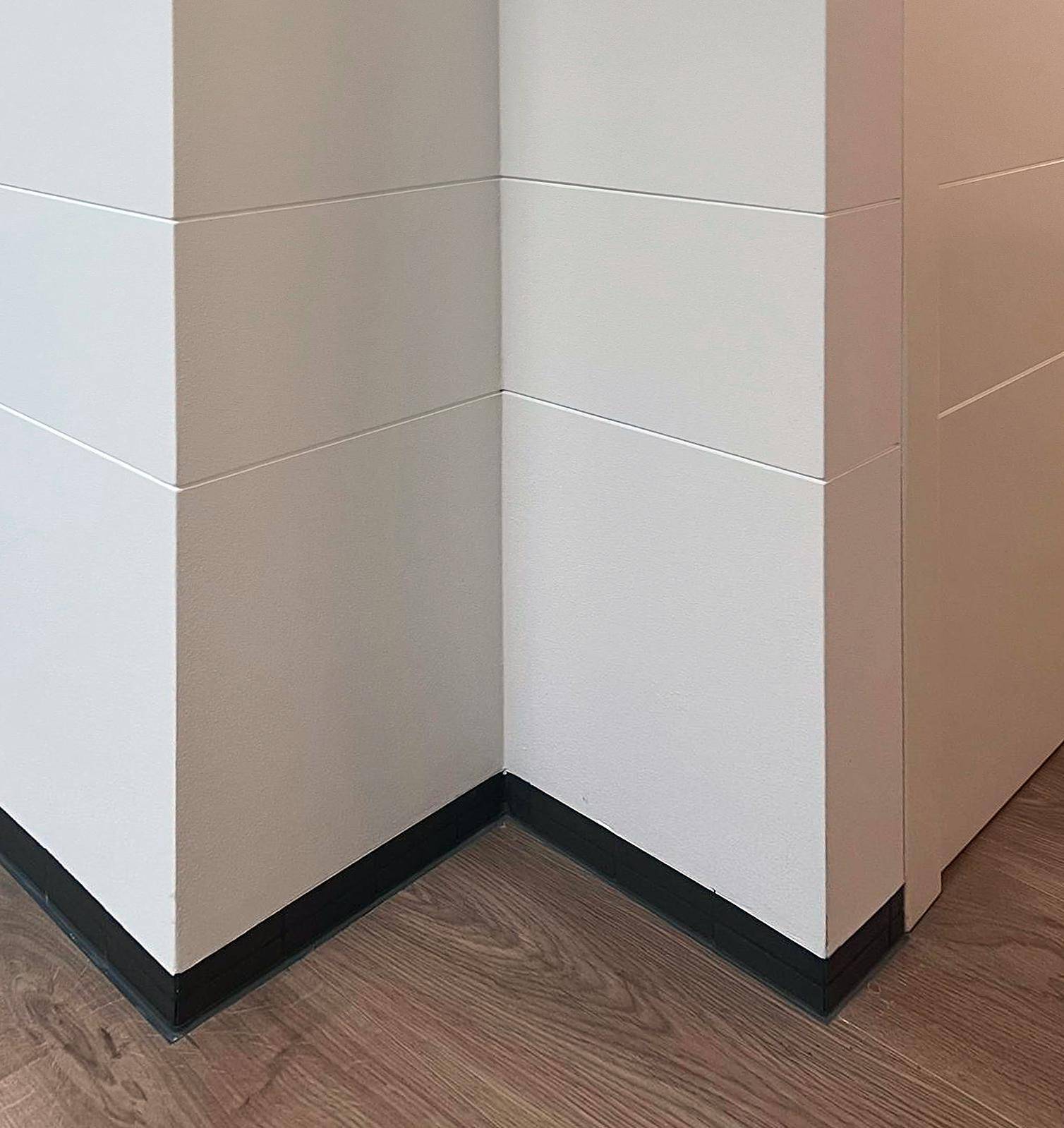 Detailansicht eines Raumecks mit Holzboden und modernen weißen Wandpaneelen.