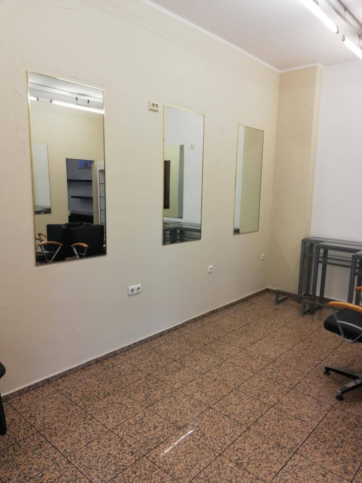 Styling-Bereich eines Salons mit mehreren Wandspiegeln und gemustertem Fliesenboden.