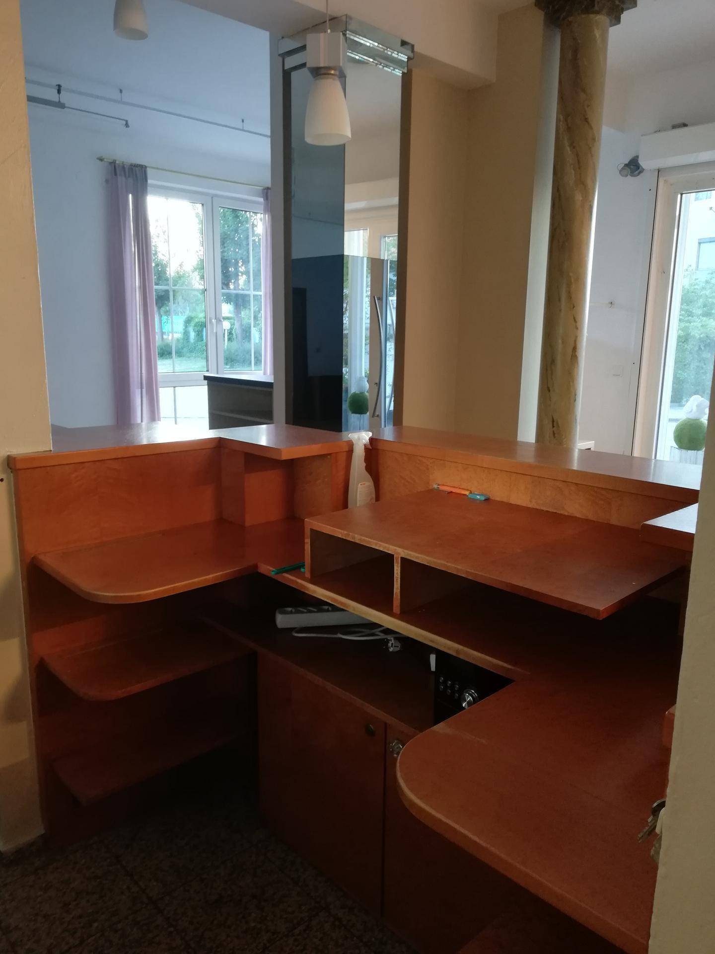 Detailansicht eines Empfangstresens aus Holz mit Ablageflächen und Blick in den Raum.