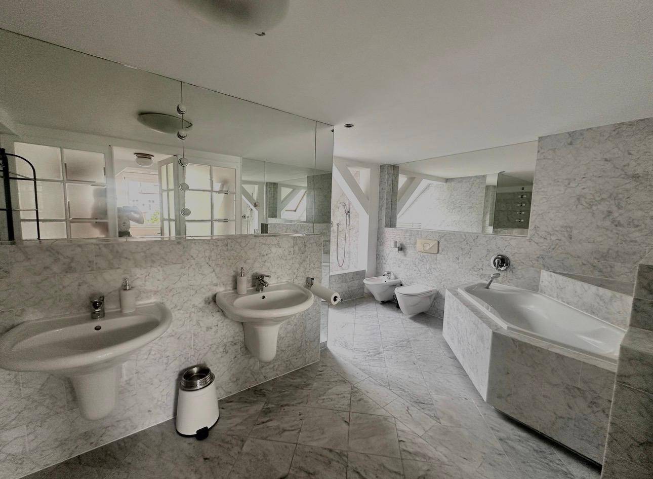 Geräumiges Badezimmer mit Doppelwaschbecken, Badewanne und Marmorfliesen.