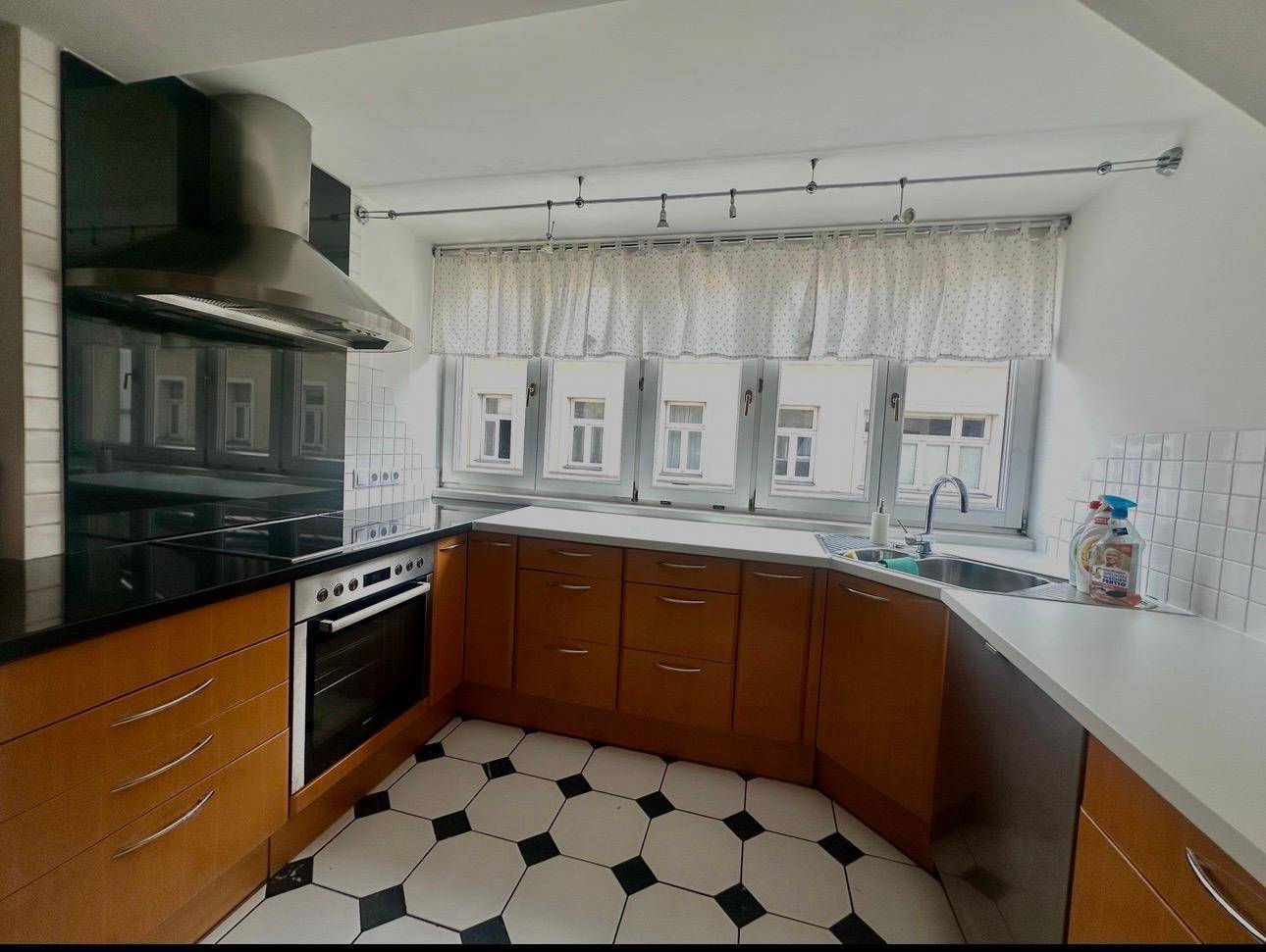Moderne Küche mit Holzschränken, Induktionskochfeld und Fensterfront.