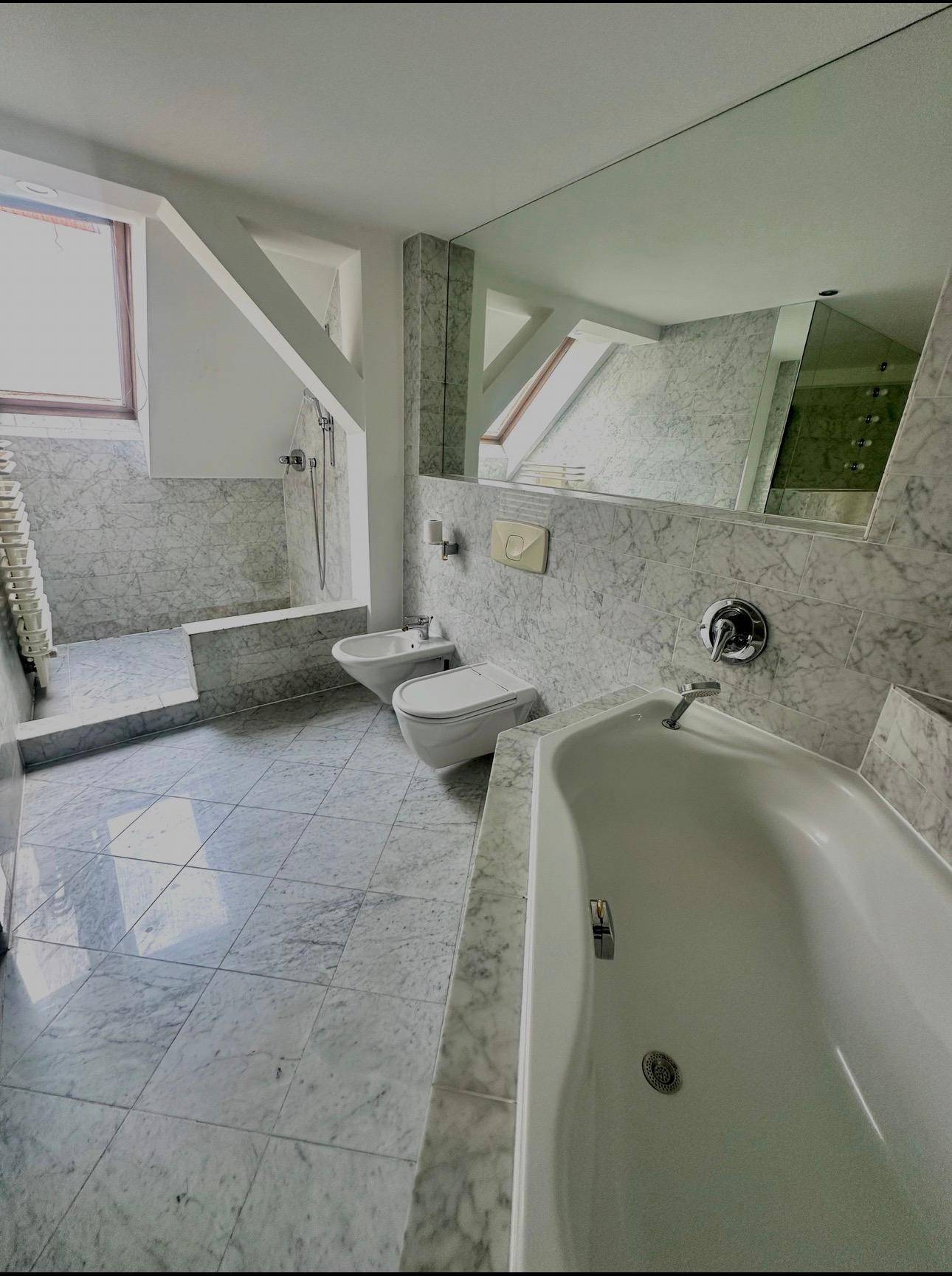 Helles Badezimmer mit Badewanne, Bidet und Marmorfliesen.