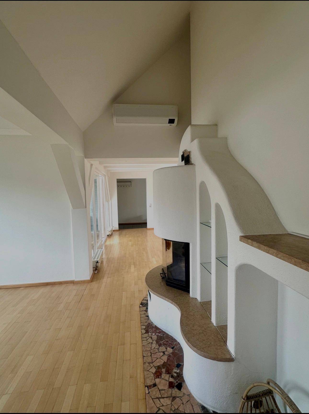 Geräumiges Wohnzimmer mit Kamin, Holzboden und Klimaanlage.