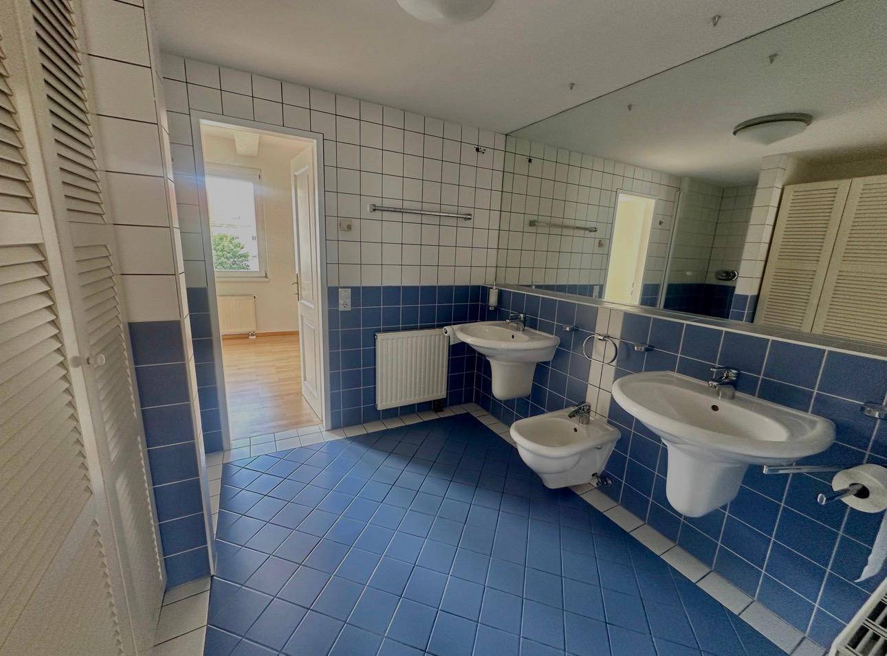 Badezimmer mit blauen und weißen Fliesen, Doppelwaschbecken und Bidet.