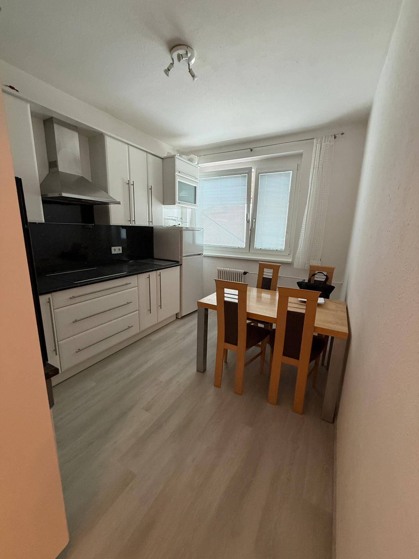 Funktionale Küche mit Essbereich, Fenster für Tageslicht und integrierten Küchengeräten.
