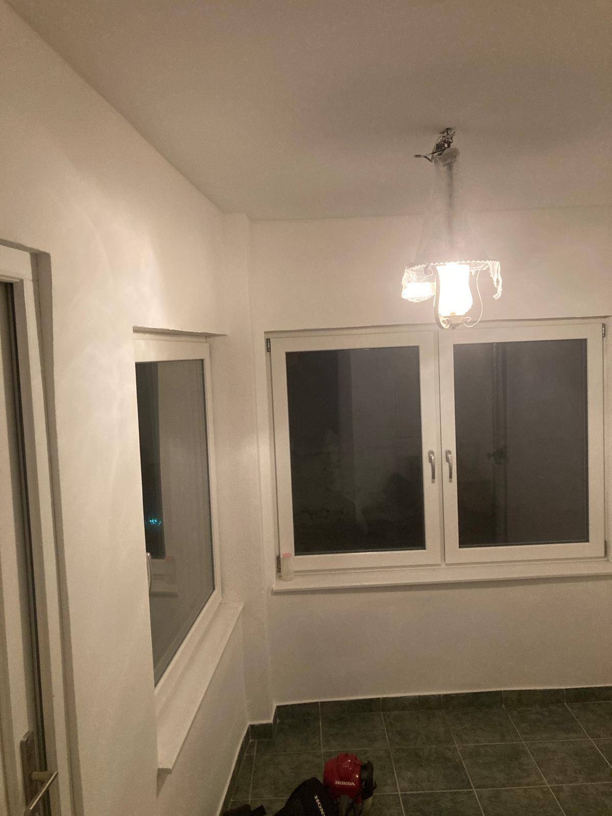 Heller Innenraum mit mehreren Fenstern und Fliesenboden, der viel natürliches Licht hereinlässt.