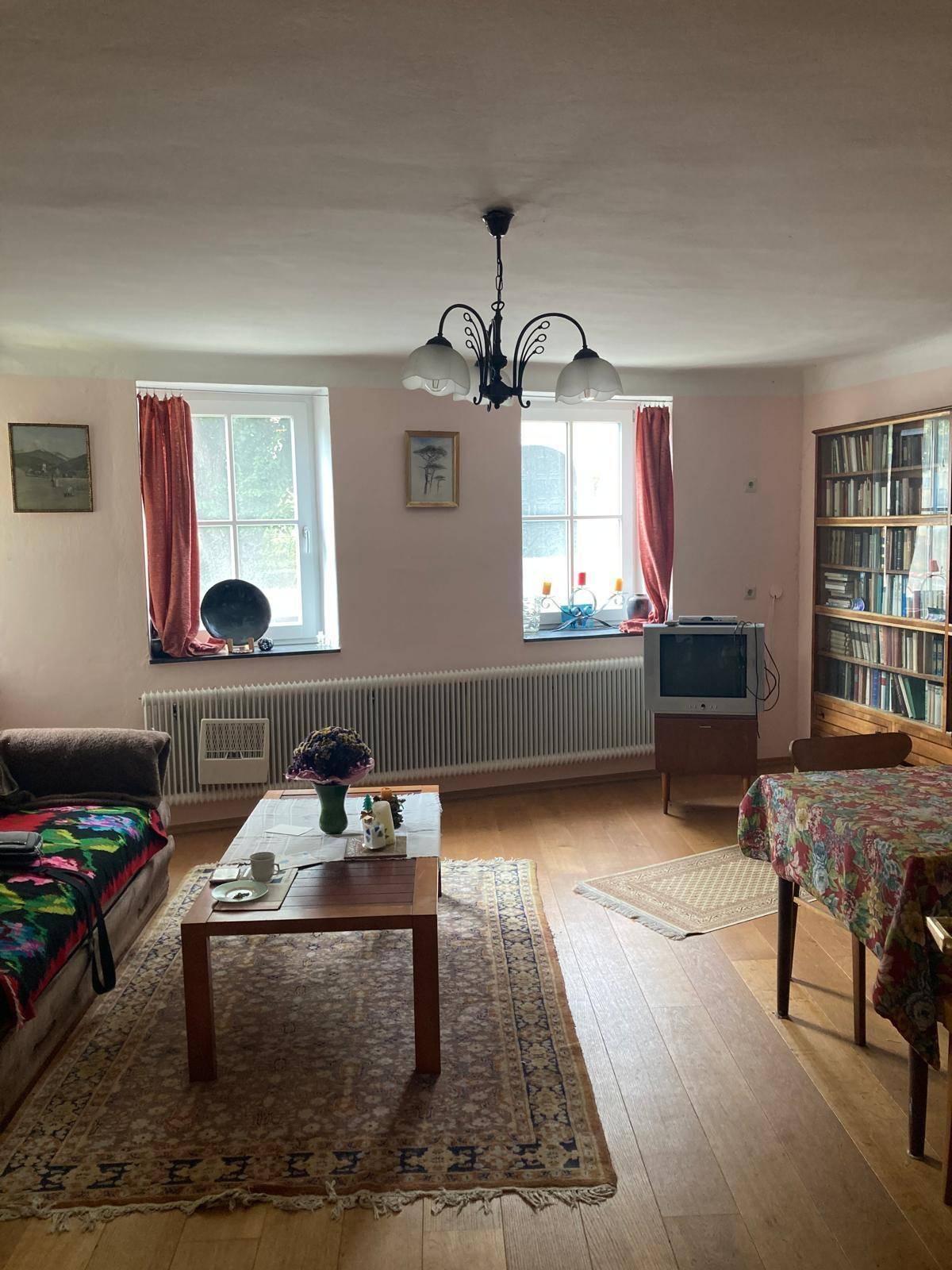 Gemütliches Wohnzimmer mit Holzfußboden, einem Bücherregal und traditioneller Einrichtung.