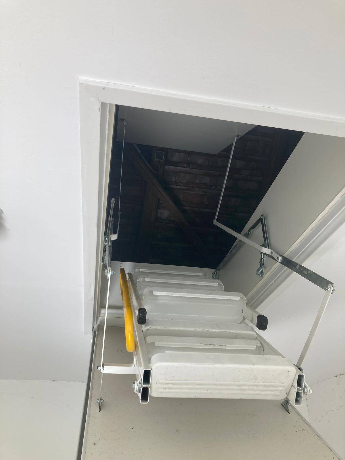 Ausziehbare Treppe zum Dachboden, die den Zugang zu einem unfertigen Bereich ermöglicht.