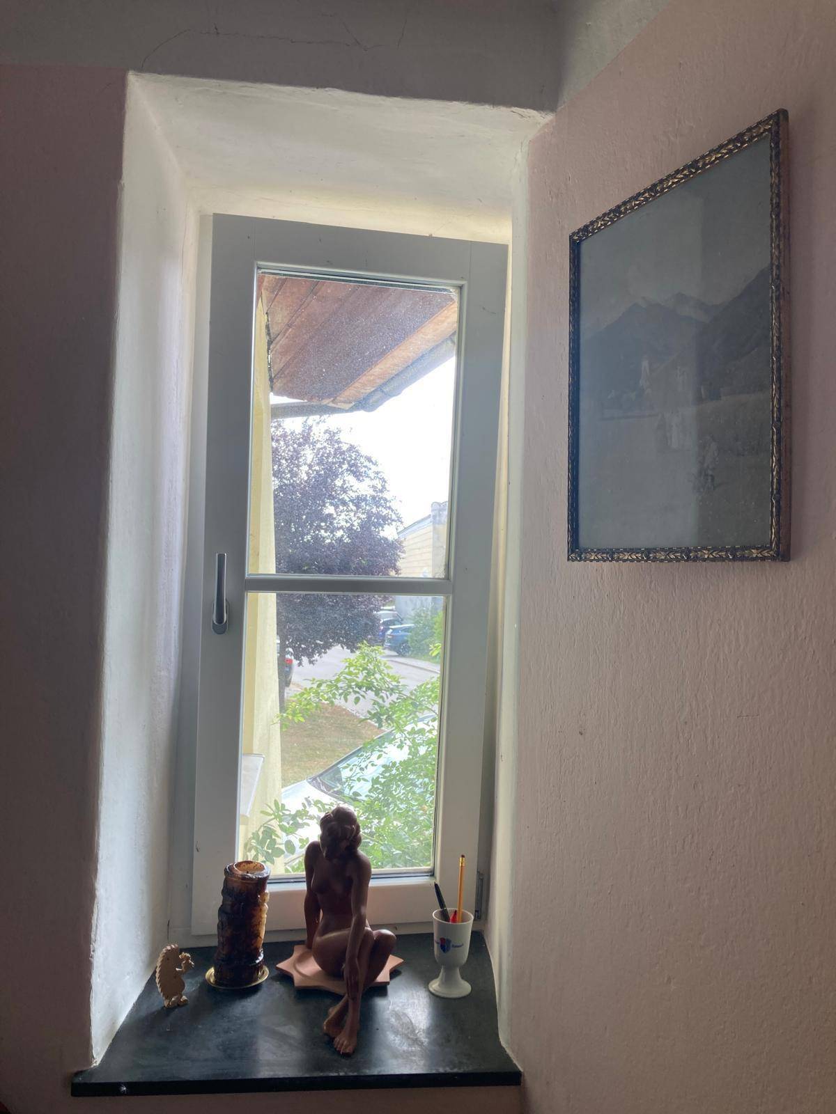Kleiner Flur mit Fenster, rosa Wänden und dekorativen Elementen auf der Fensterbank.