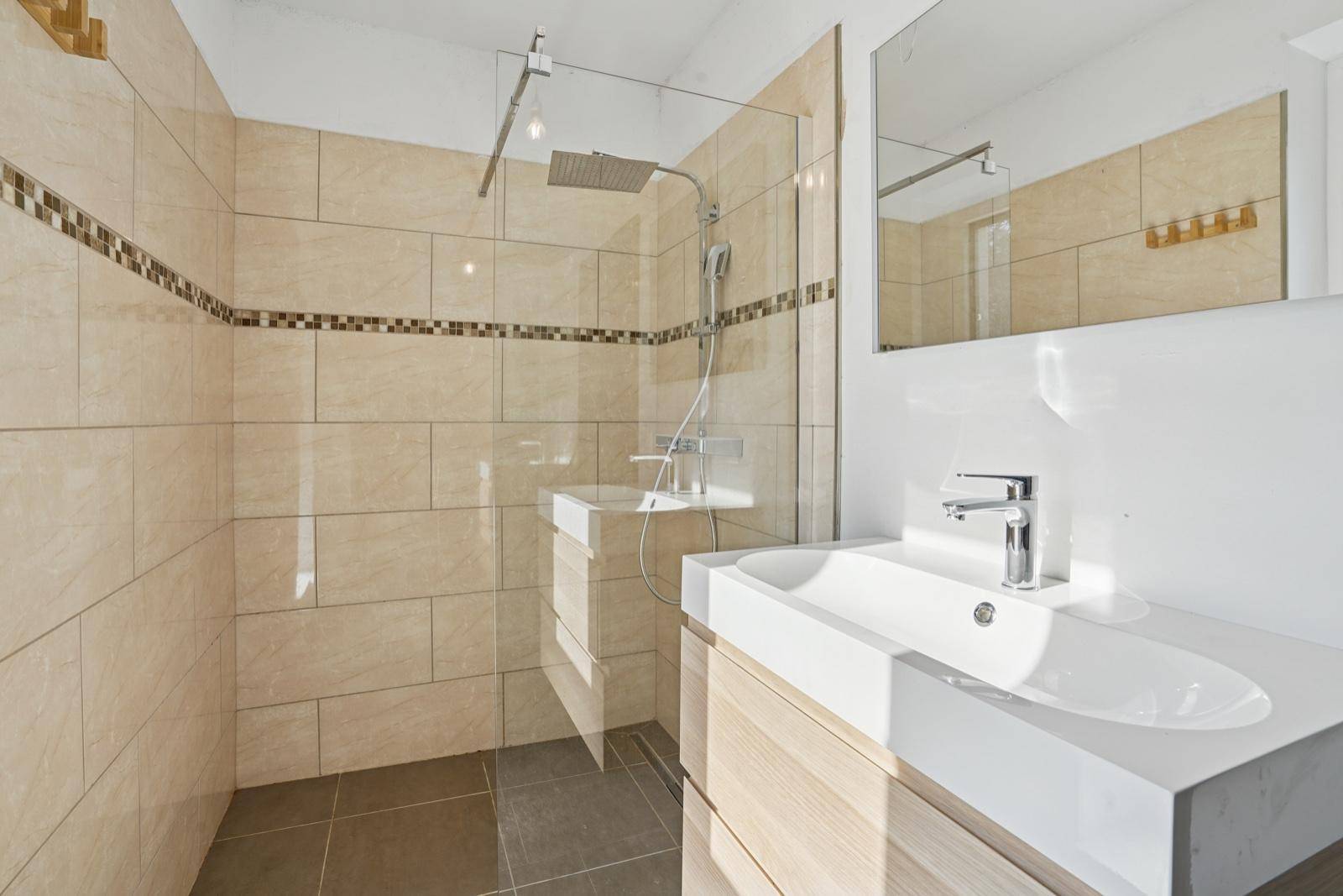 Modernes Badezimmer mit begehbarer Dusche, Waschtisch und hellen Fliesen.