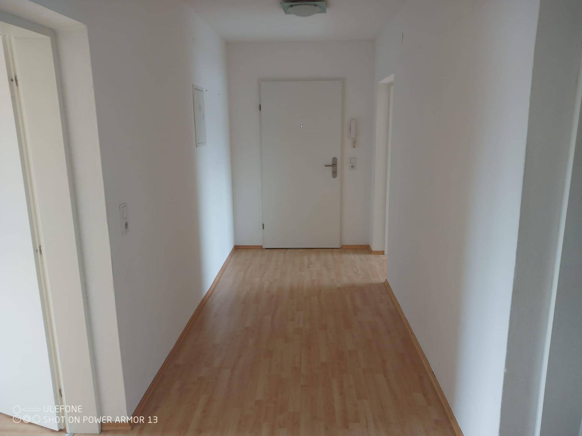 Heller Flur mit Laminatboden und Eingangstür zur Wohnung.