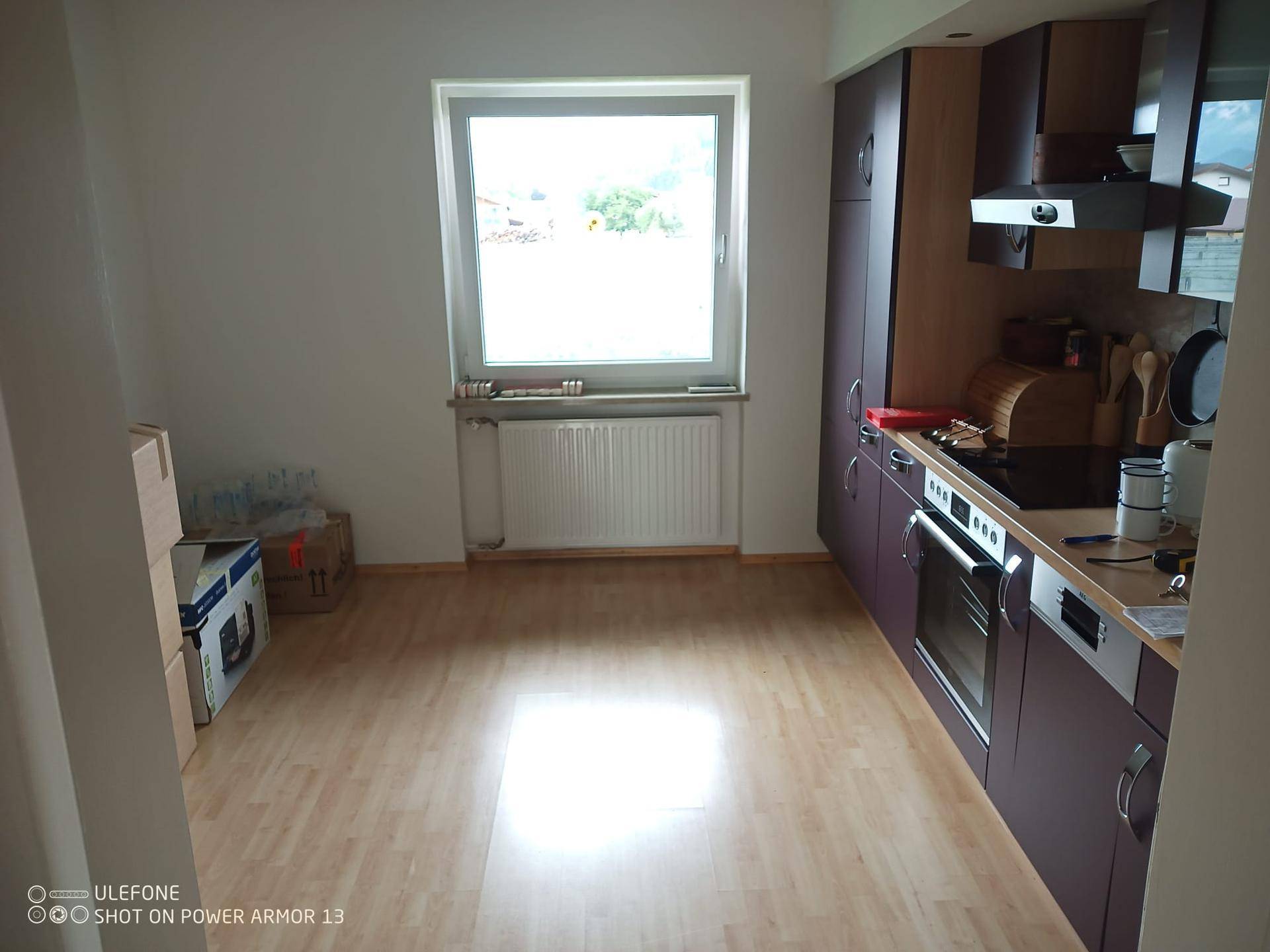 Moderne Küche mit dunklen Einbauschränken, Laminatboden und Fenster.