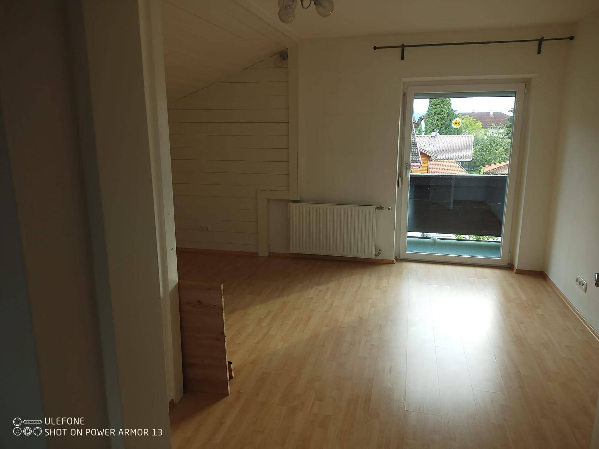 Geräumiges Dachgeschosszimmer mit Laminatboden und direktem Zugang zu einem Balkon.