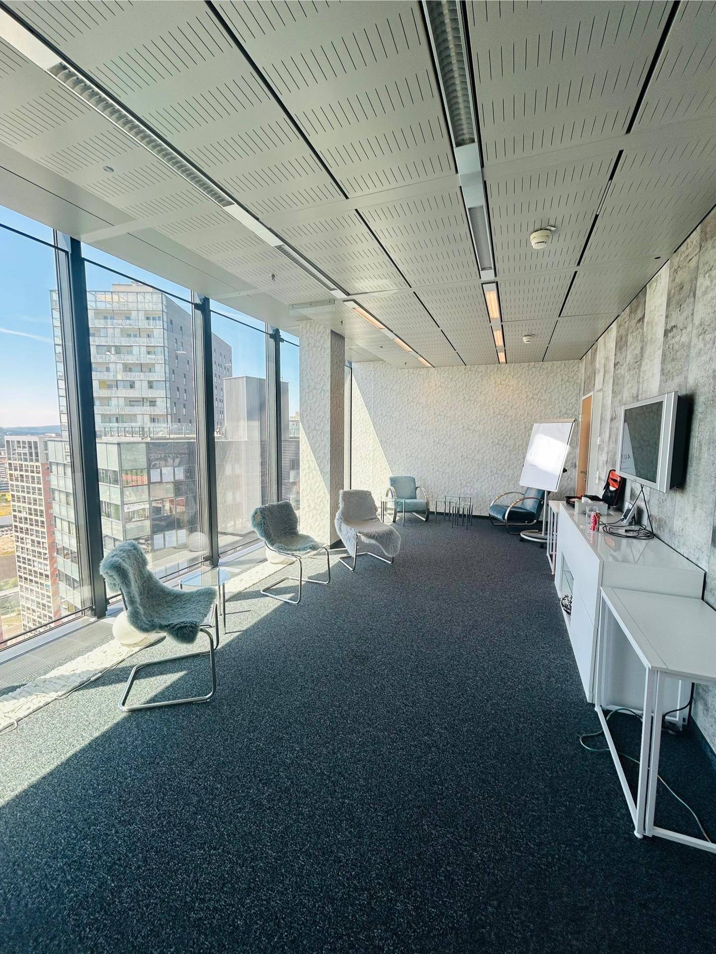 Geräumiger Büroraum mit Teppichboden, modernen Stühlen und beeindruckendem Ausblick durch die Glasfassade.