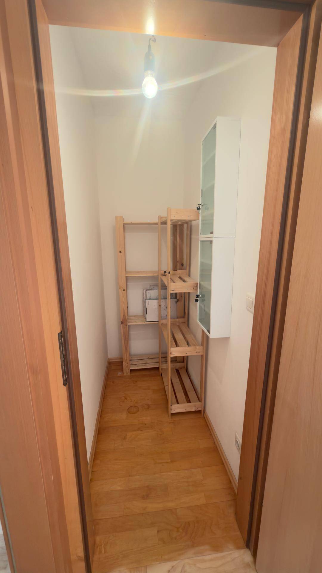 Praktischer Abstellraum mit Holzregalen und zusätzlichen Hängeschränken für Stauraum.