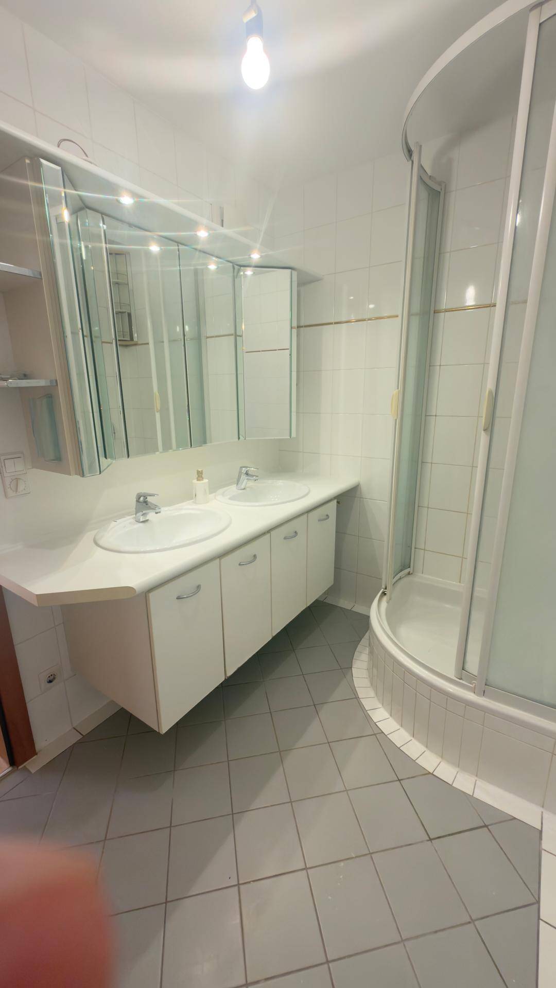 Modernes Badezimmer mit Doppelwaschbecken, Duschkabine und hellen Fliesen.