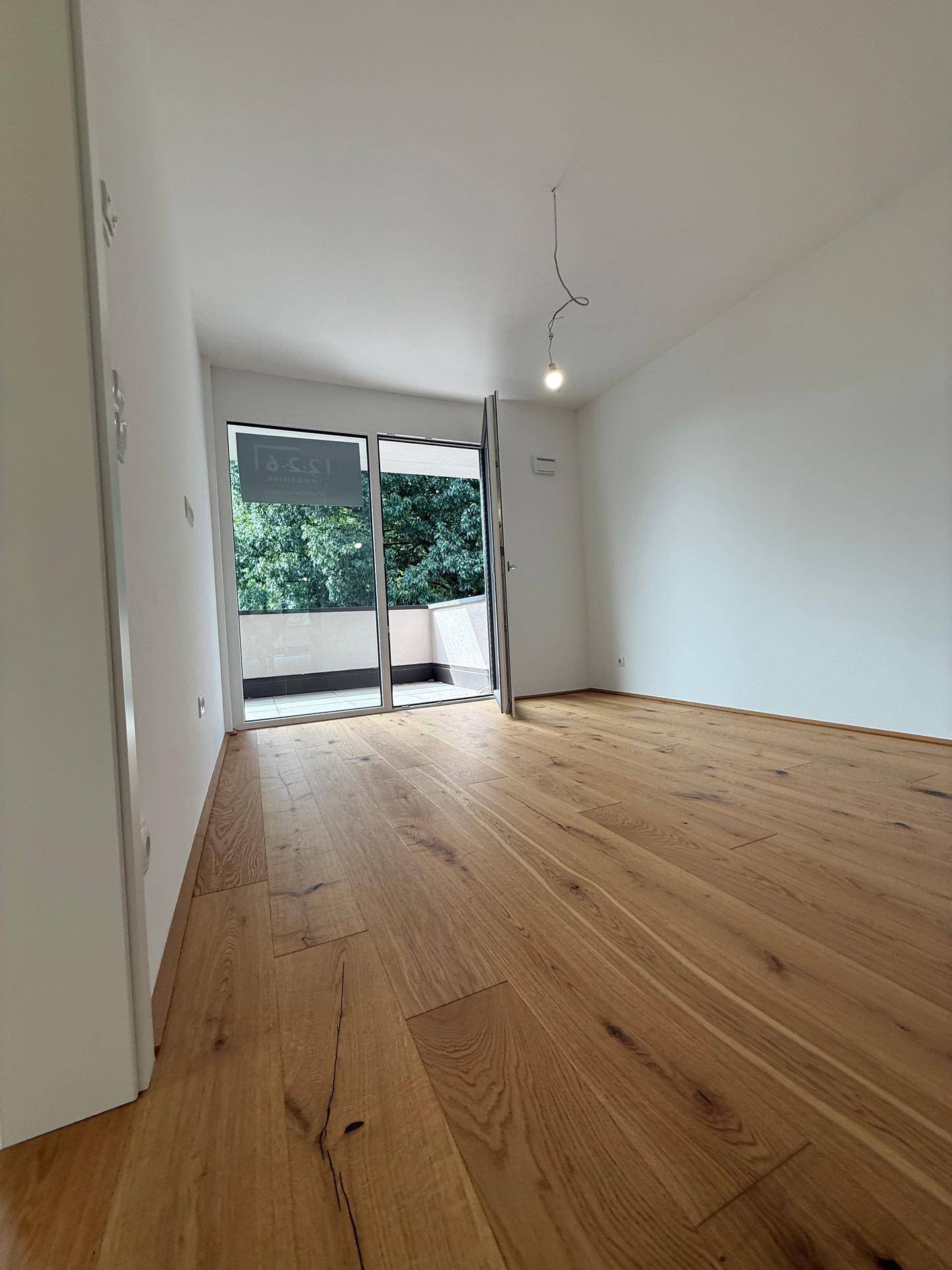Lichtdurchflutetes Schlafzimmer mit Holzboden und direktem Zugang zum Balkon.