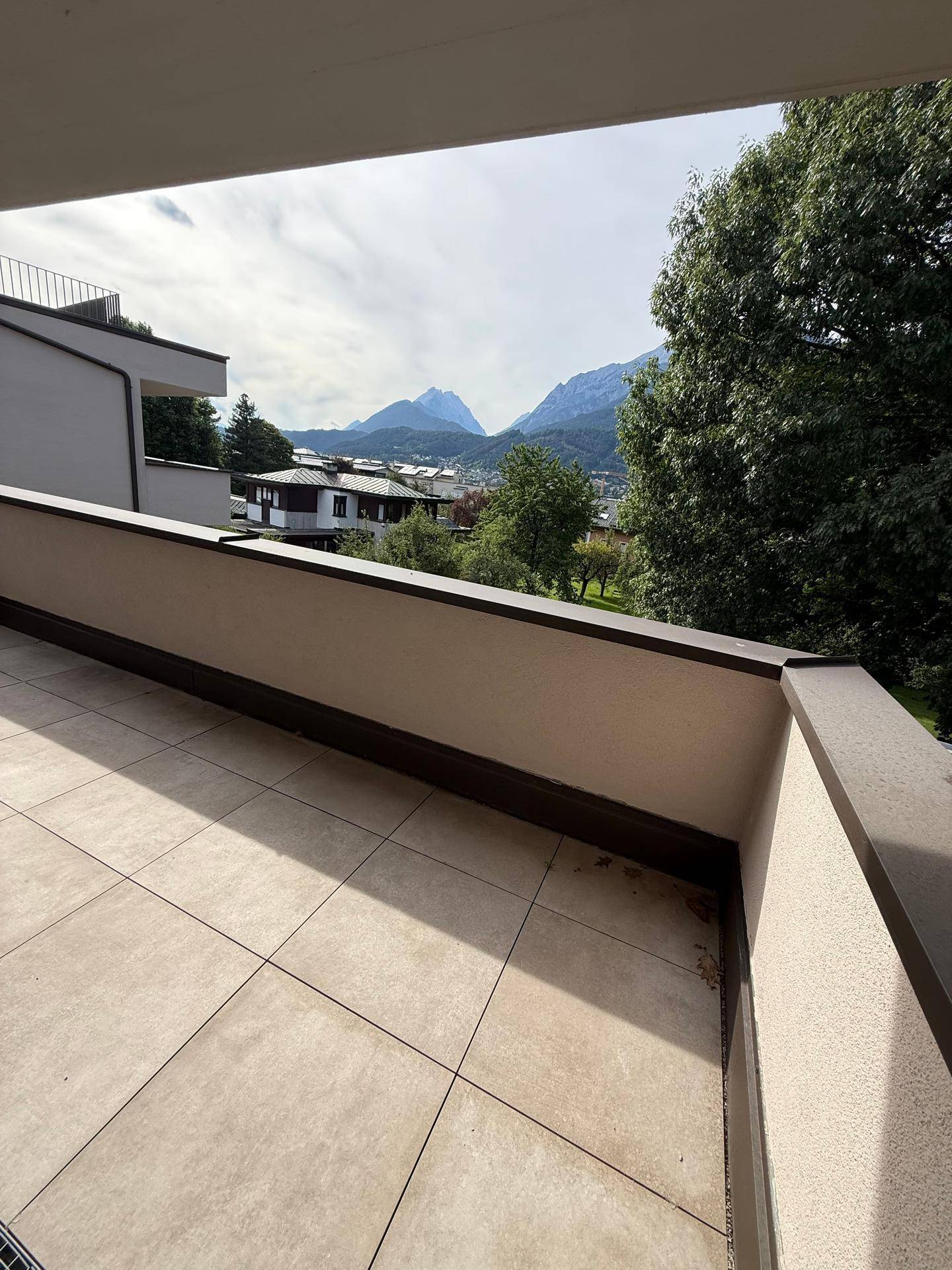 Großer Balkon mit Fliesenboden und weitem Blick auf die Berge und die Umgebung.