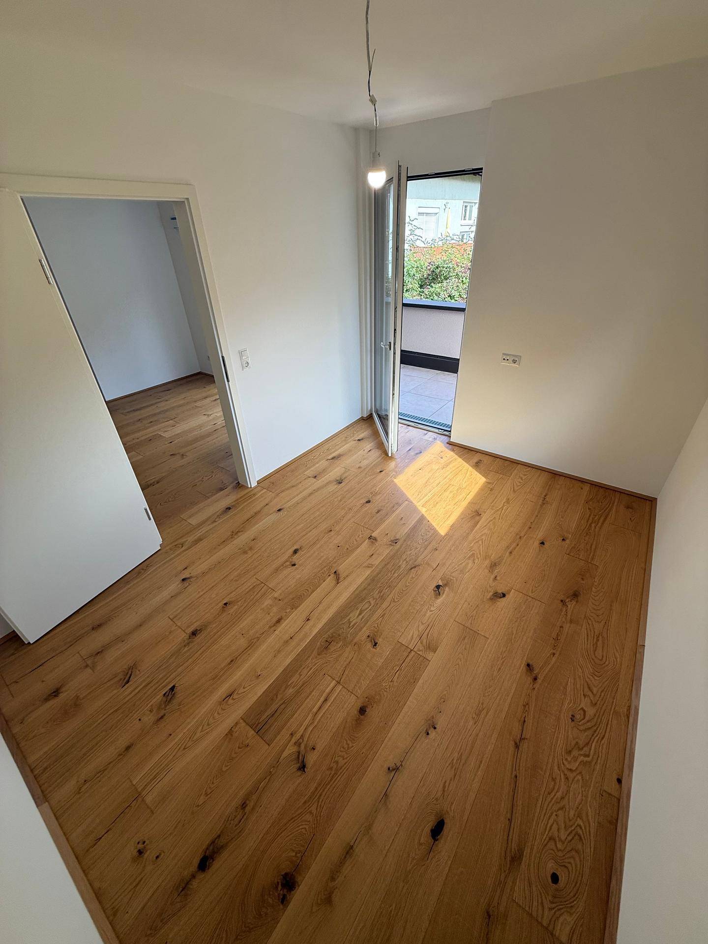 Gemütliches Zimmer mit Holzboden und direktem Zugang zu einem kleinen Balkon.