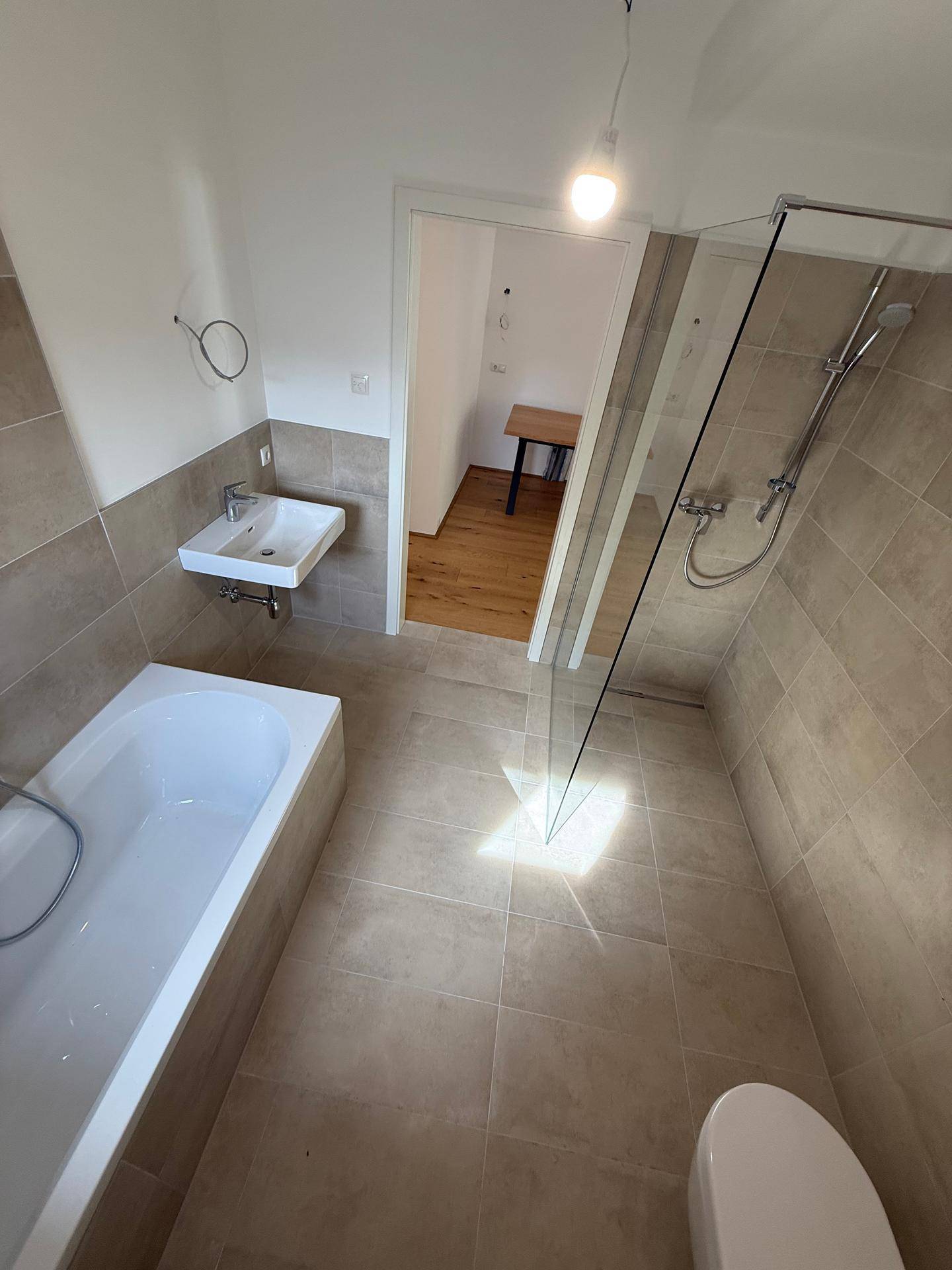 Helles Badezimmer mit Badewanne, Duschbereich und modernem Waschbecken.