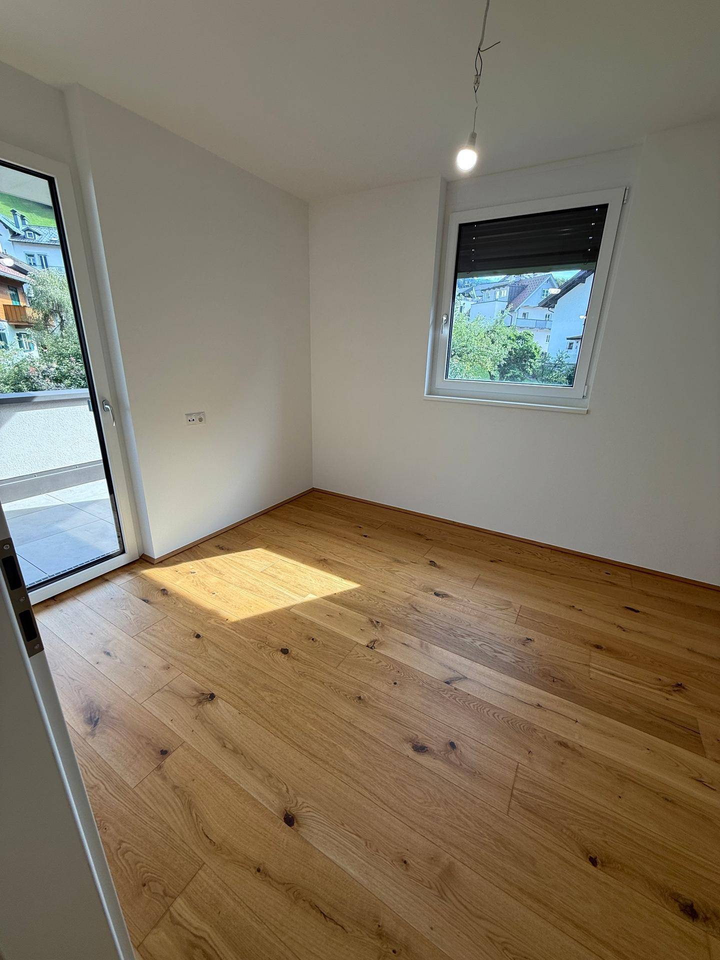 Helles Schlafzimmer mit Holzboden und Fenster, ideal für Ruhe und Entspannung.