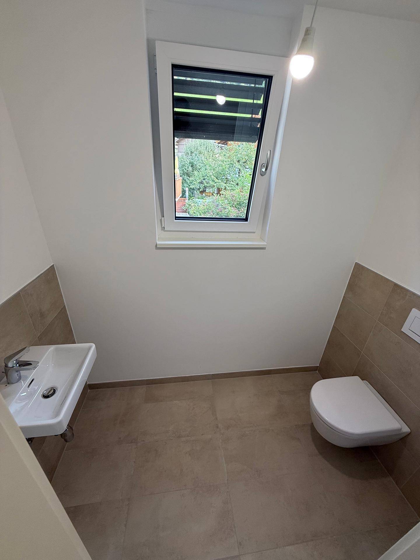 Modernes Gäste-WC mit Wand-WC, kleinem Waschbecken und Fenster.