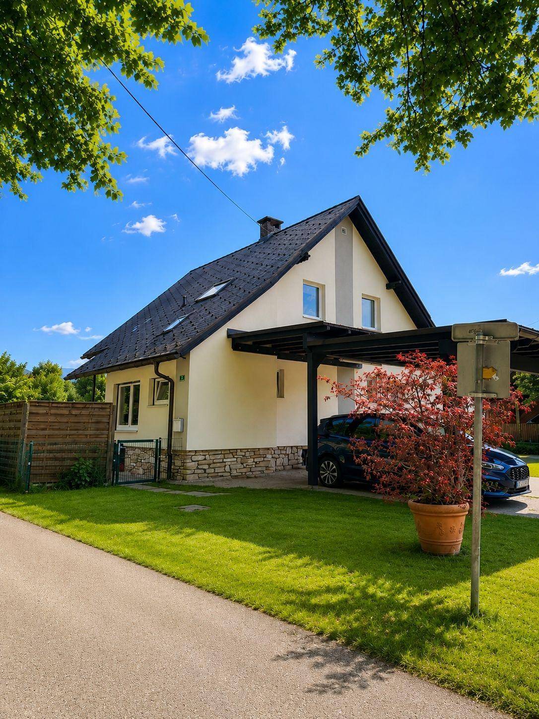 Ansicht des Einfamilienhauses mit Carport, Zufahrt und einem kleinen Vorgartenbereich.
