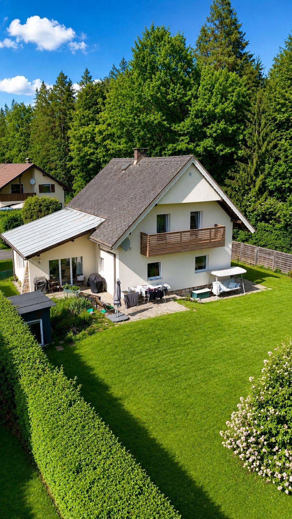 Vogelperspektive eines gepflegten Einfamilienhauses mit weitläufigem Rasen und umgebenden Bäumen.