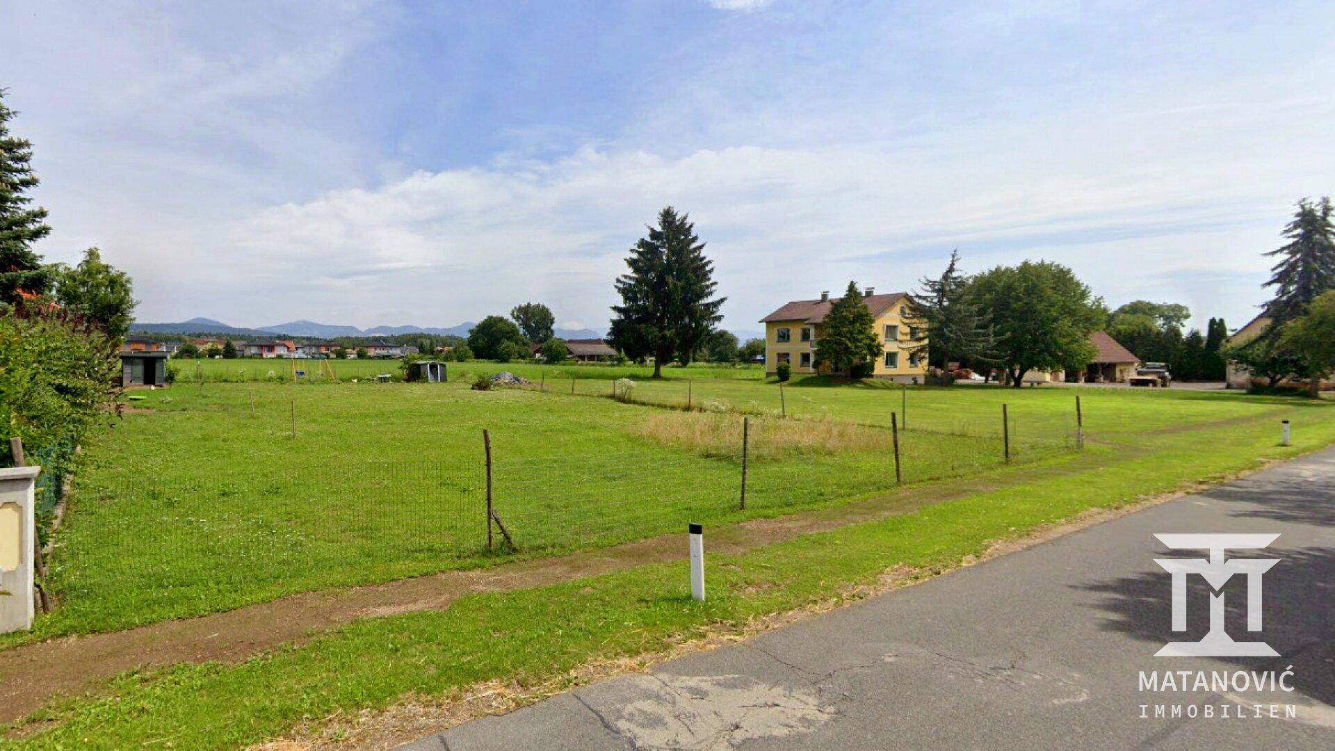 Weitläufige Grünfläche mit Blick auf die umliegende Landschaft und entfernte Häuser.