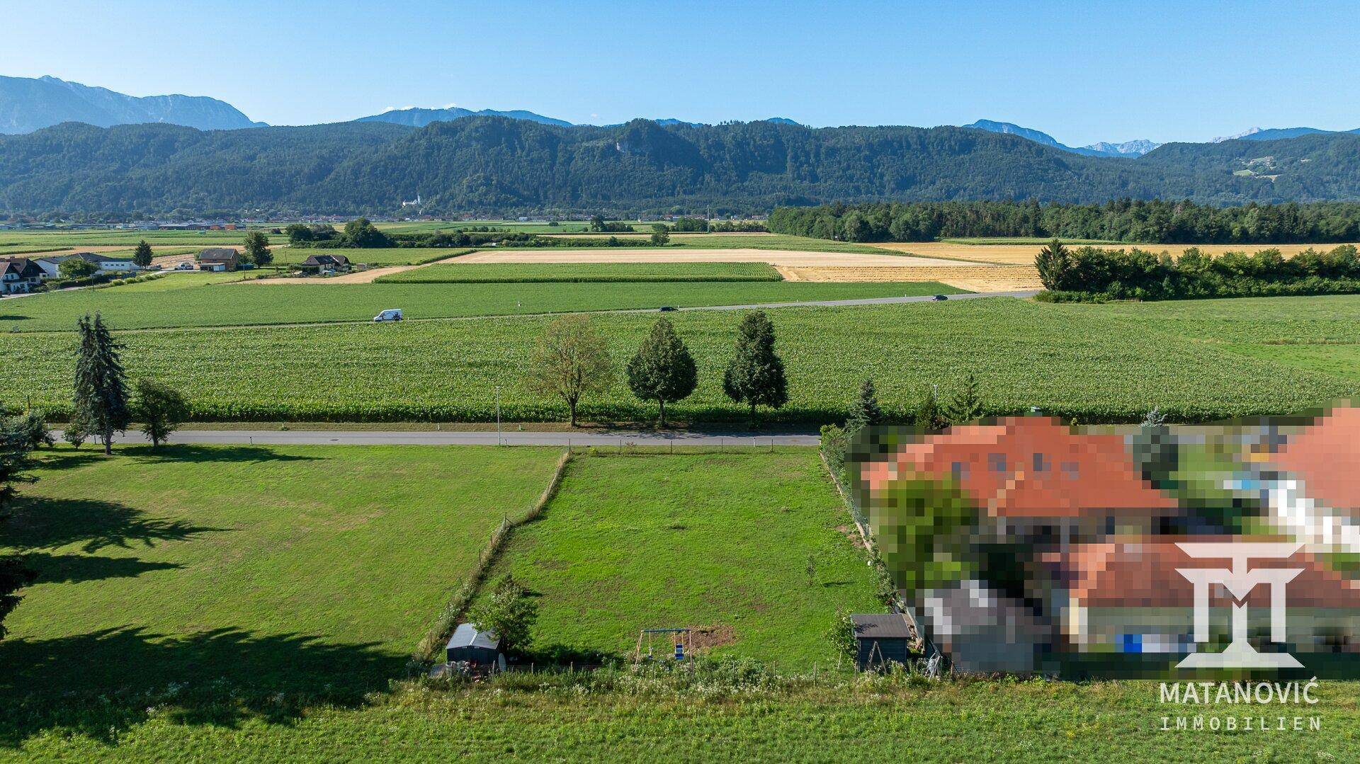 Panoramablick aus der Luft auf grüne Felder, eine Straße und eine Bergkette am Horizont.