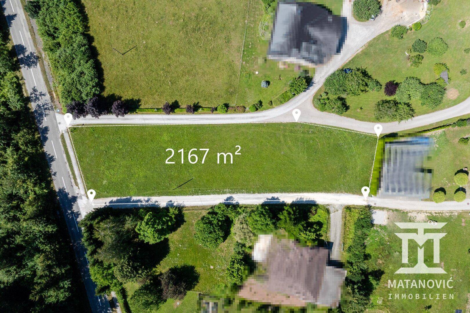 Luftaufnahme eines großen, grünen Grundstücks von 2167 m² mit umliegenden Wegen und Häusern.
