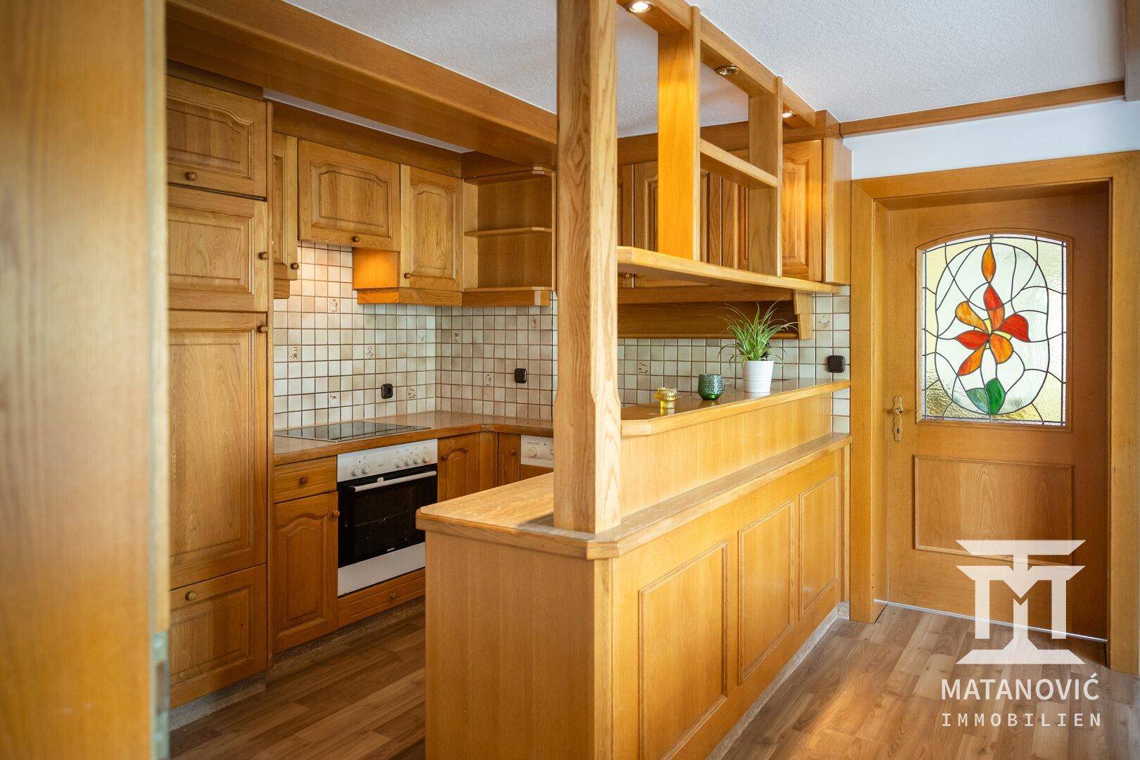 Gemütliche Holzküche mit integriertem Backofen und Kochfeld, sowie einer dekorativen Glastür.