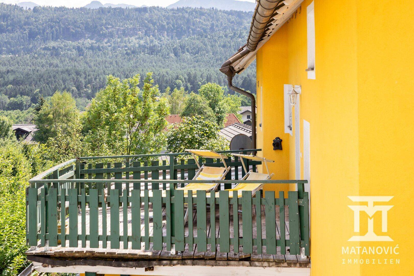 Balkon mit Holzgeländer und zwei Sonnenliegen, bietet einen schönen Blick ins Grüne.