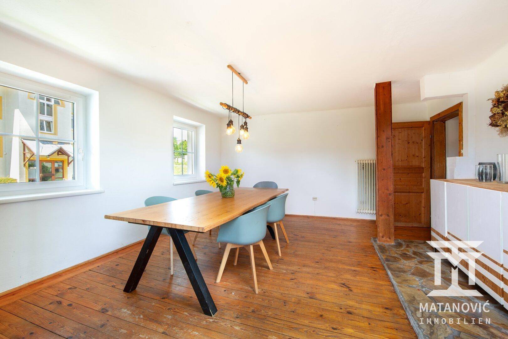 Helles Esszimmer mit rustikalem Dielenboden, Holztisch und viel natürlichem Lichteinfall.