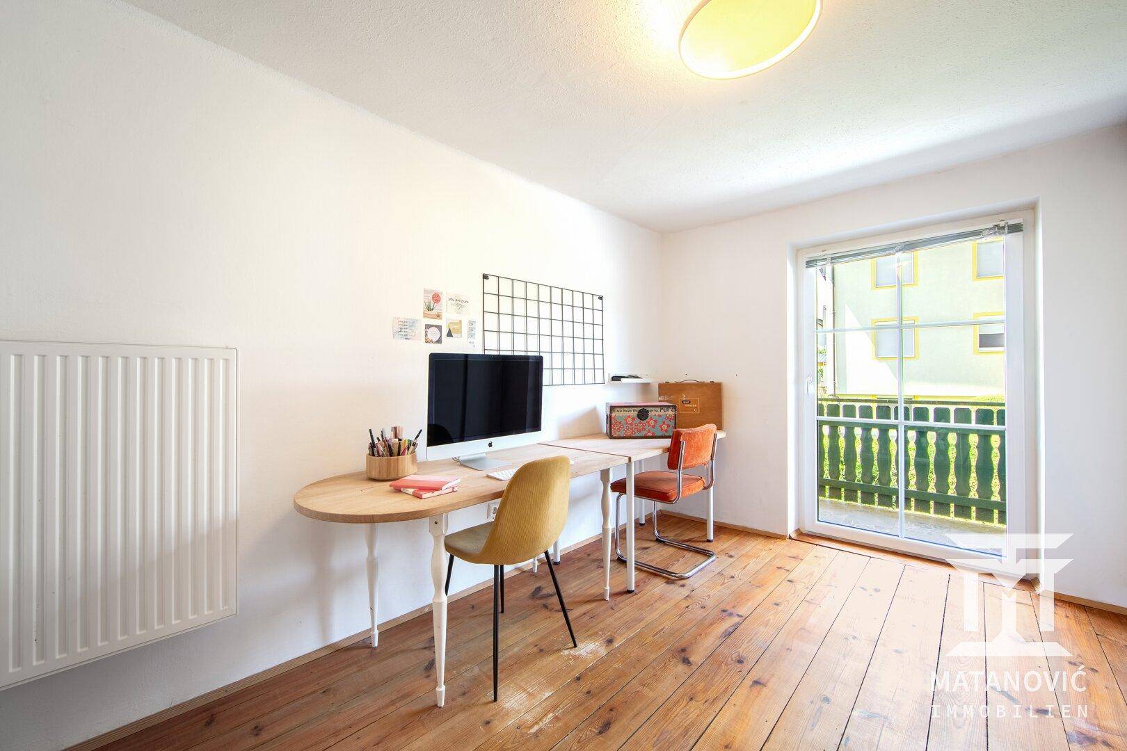 Arbeitszimmer mit Schreibtisch, Dielenboden und Balkonzugang, ideal für Home-Office.