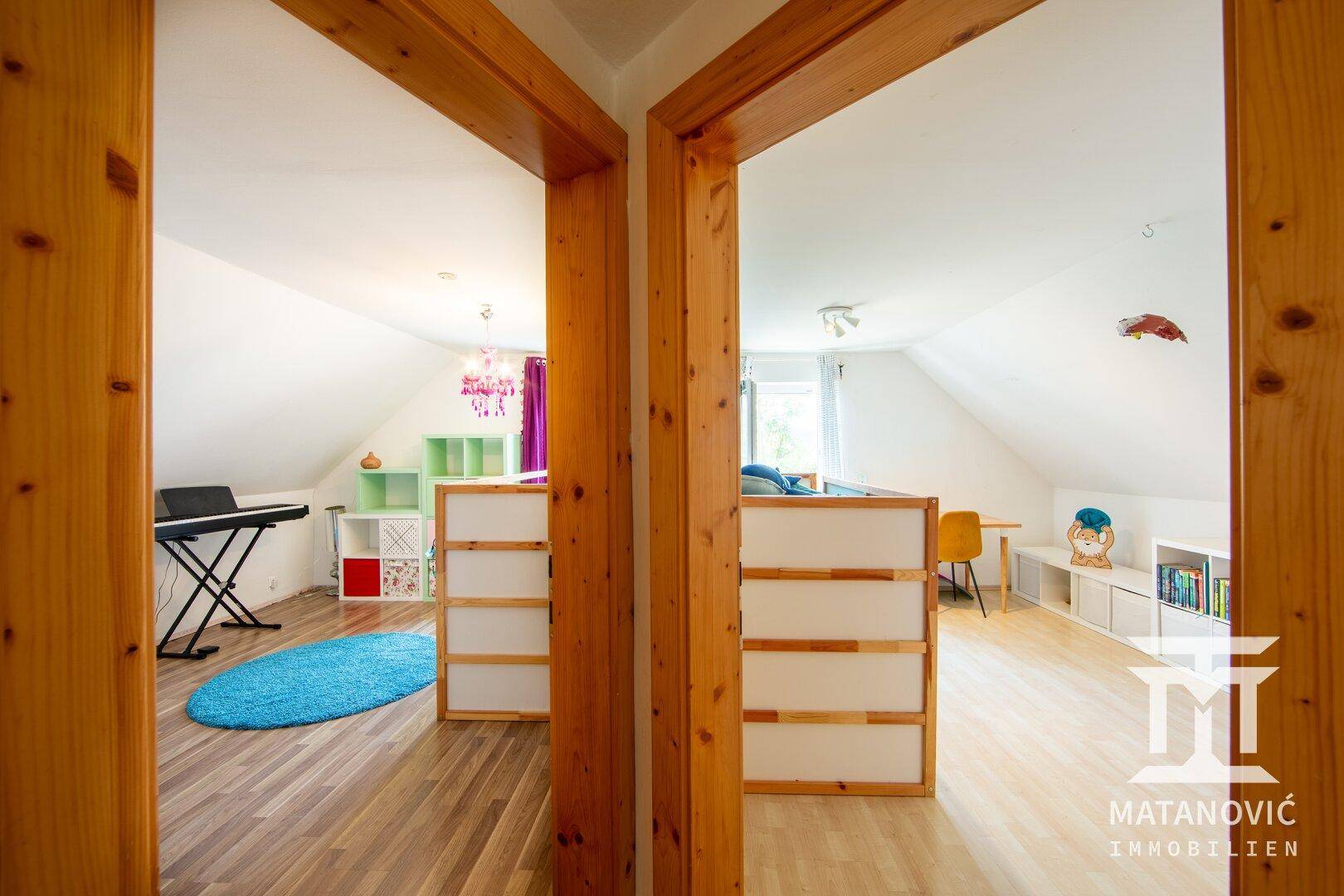 Helles Kinderzimmer oder Spielbereich mit schrägen Wänden und hellem Laminatboden.